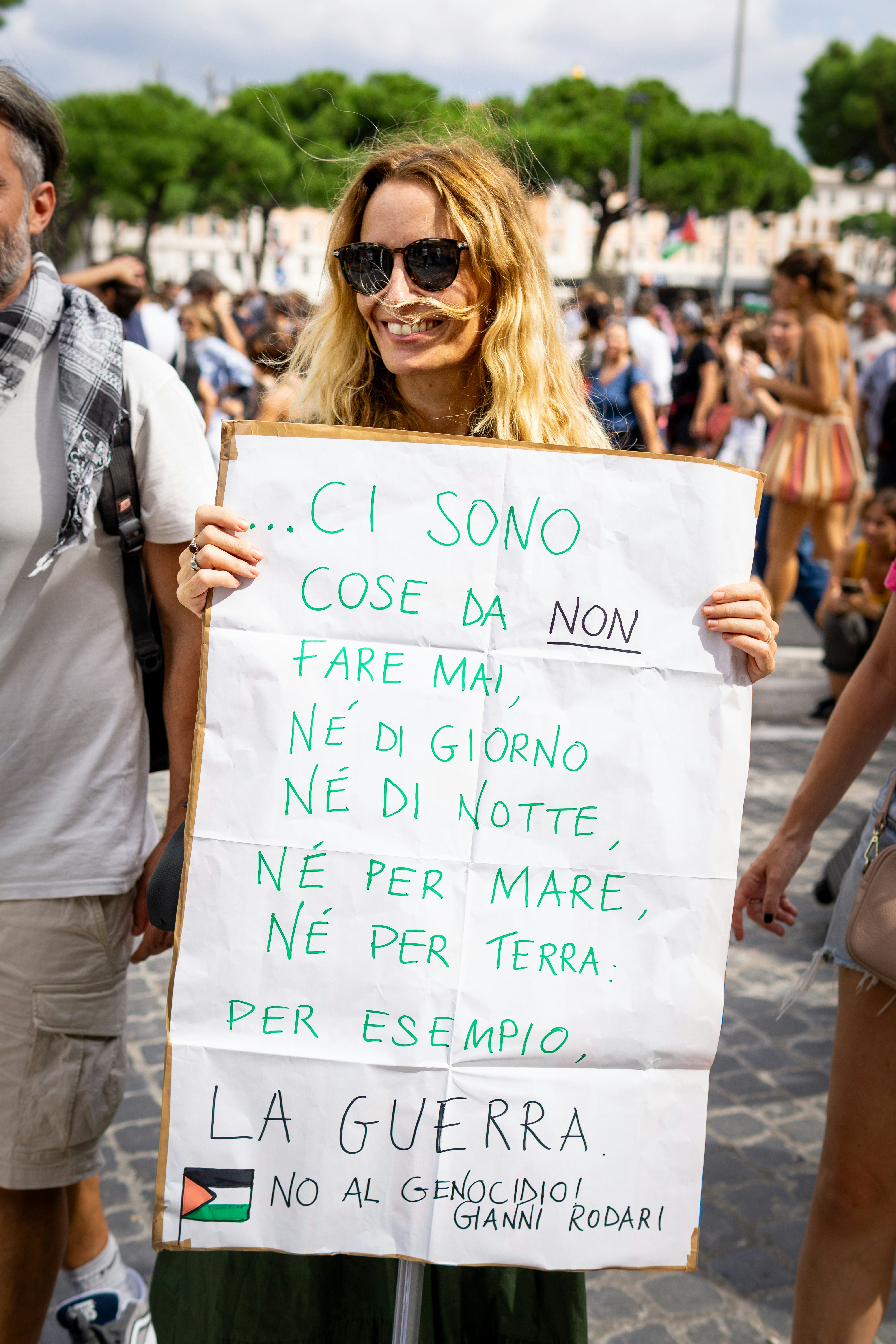 Woman holds sign protesting war at a public gathering.