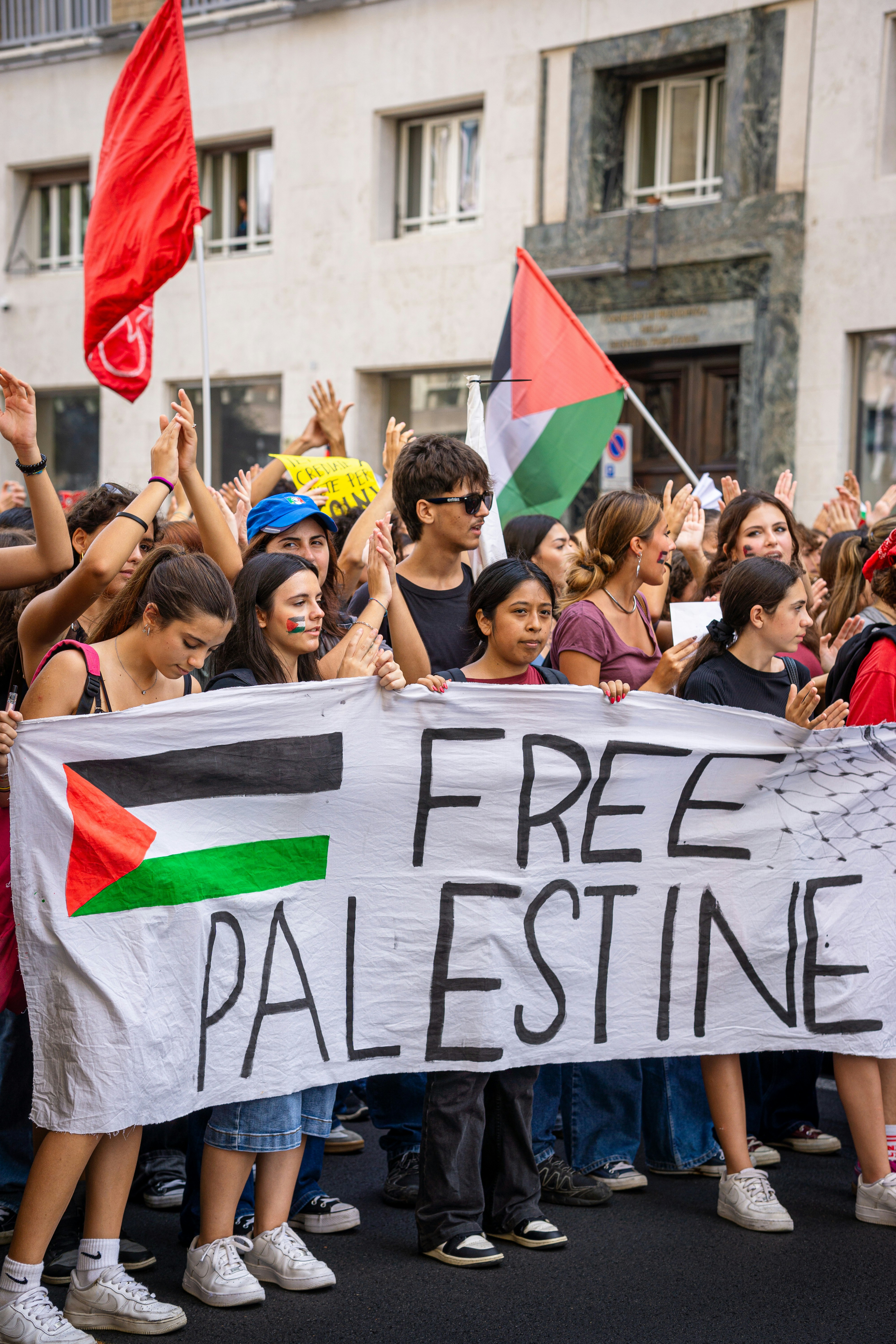 Manifestantes seguram uma faixa de "Palestina livre" com bandeiras.