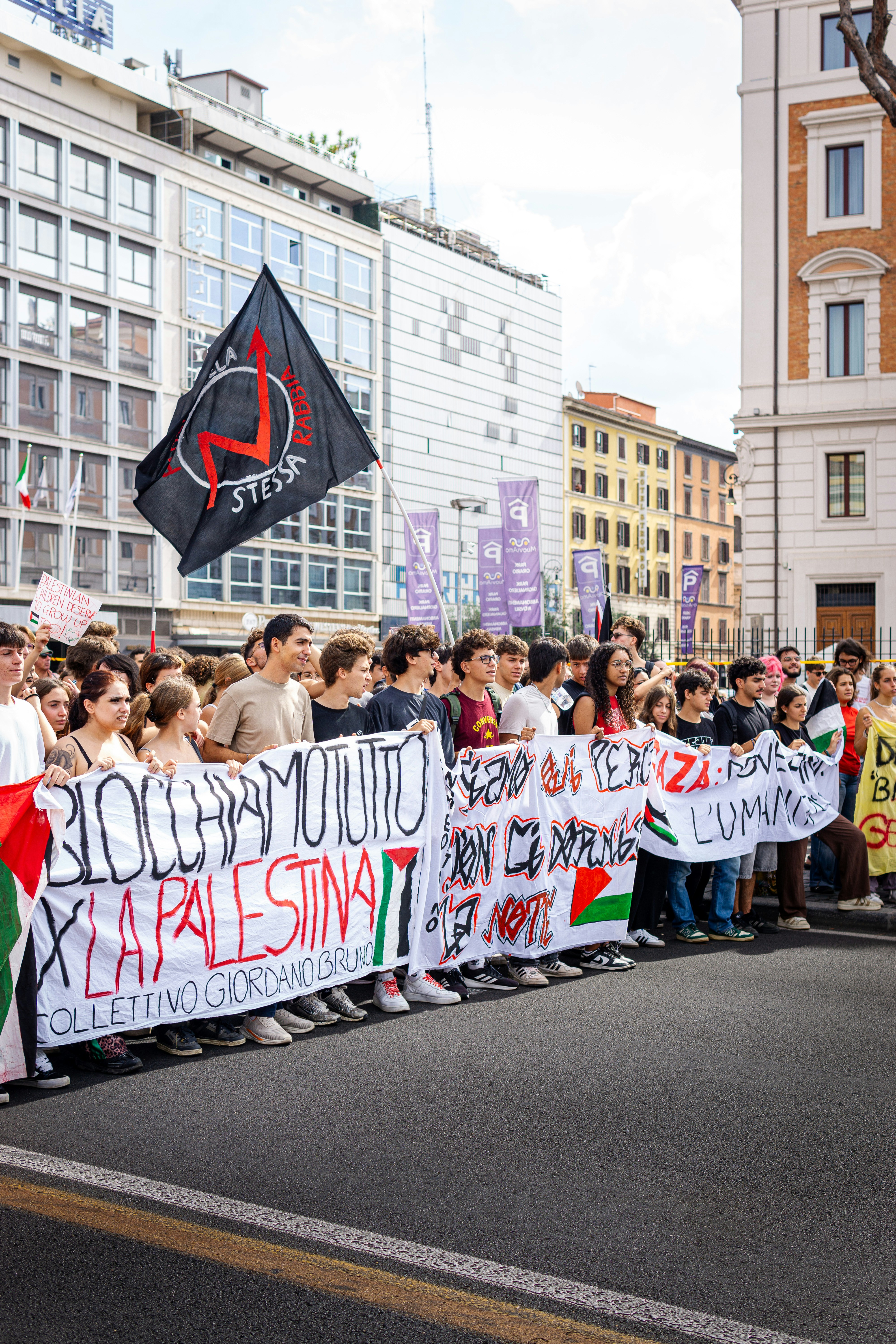 Protesters hold banners supporting palestine in a street protest.