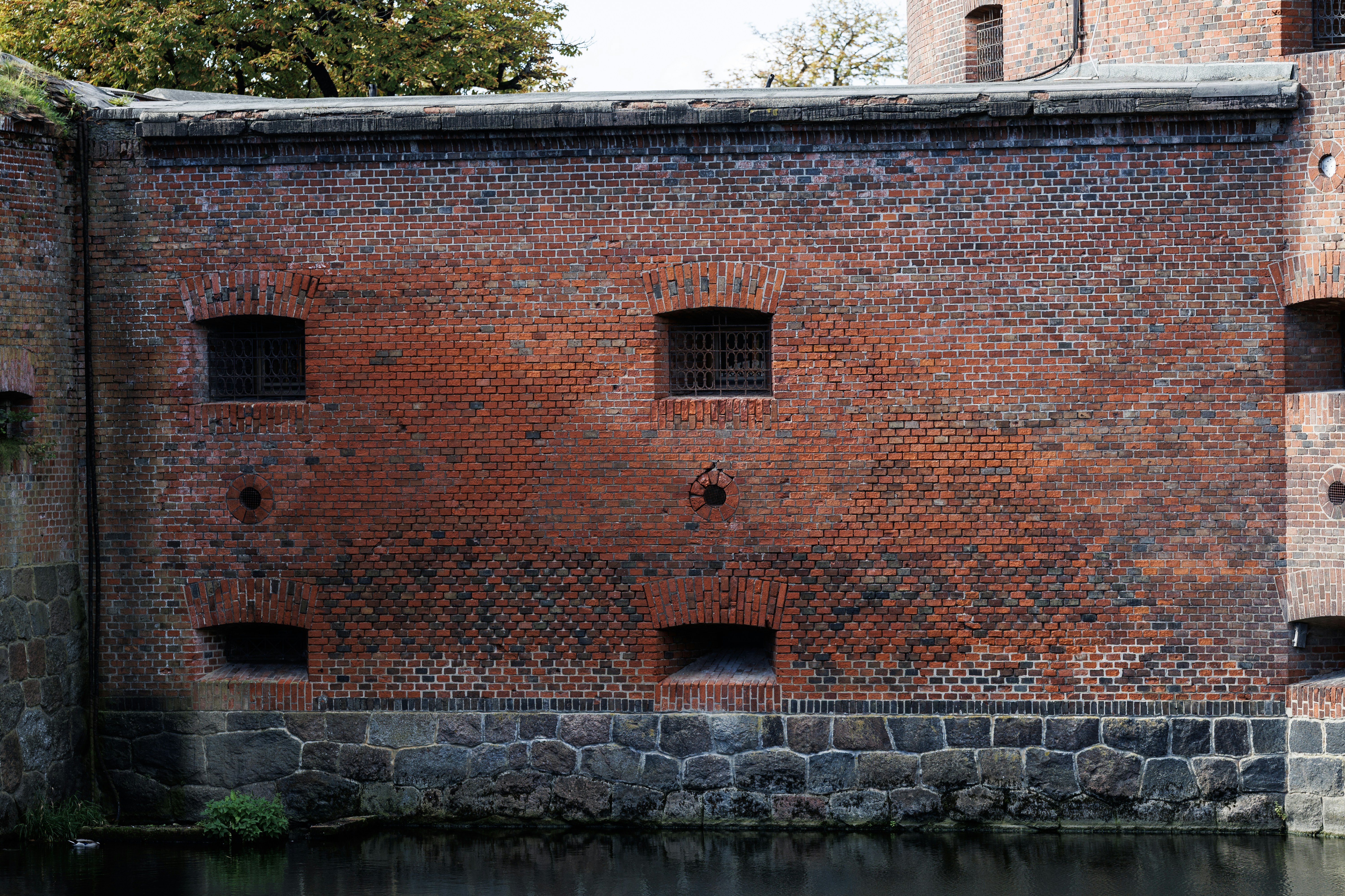 Old brick wall with small windows and water below