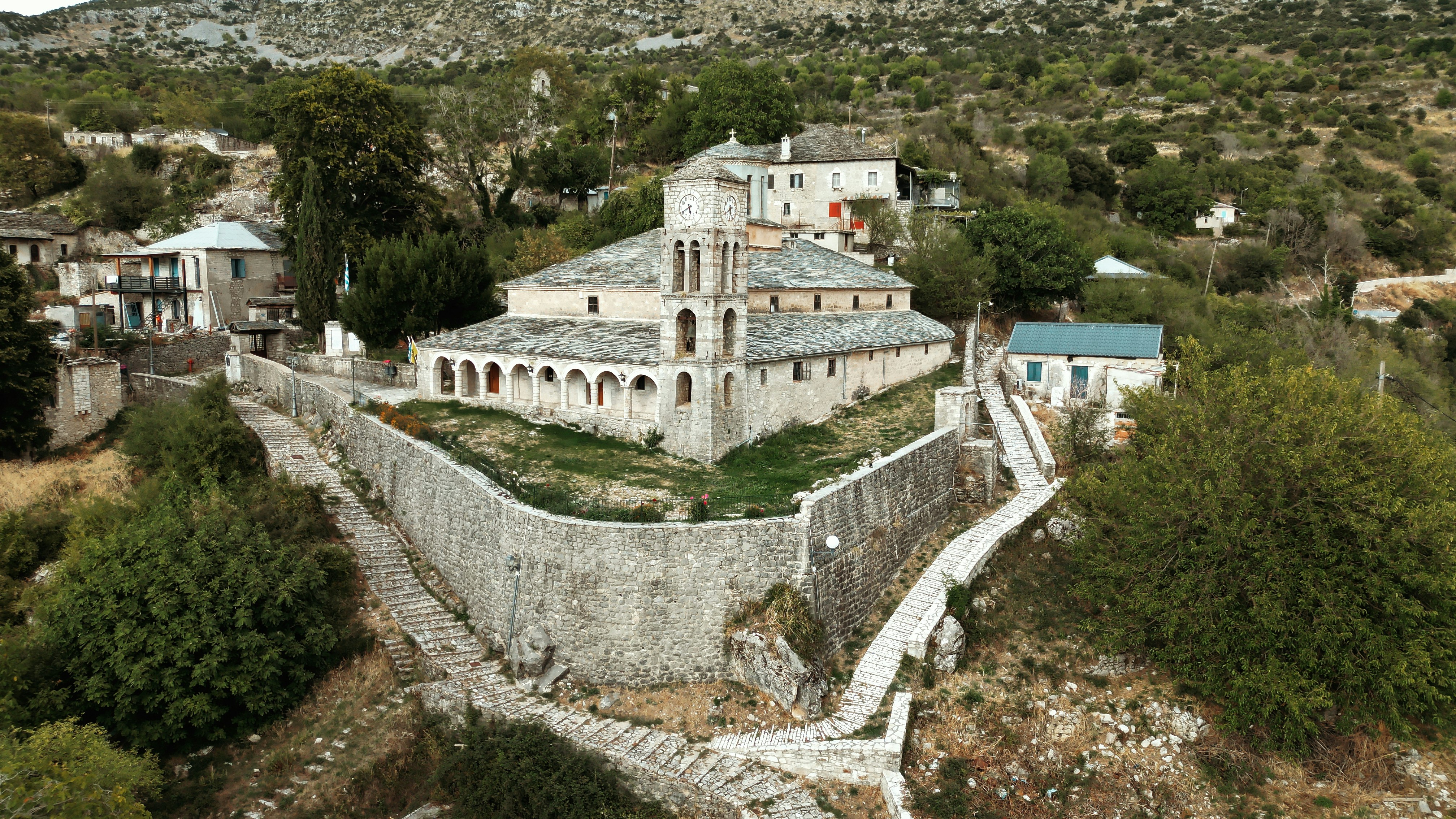 Stone fortress and buildings on a green hillside.