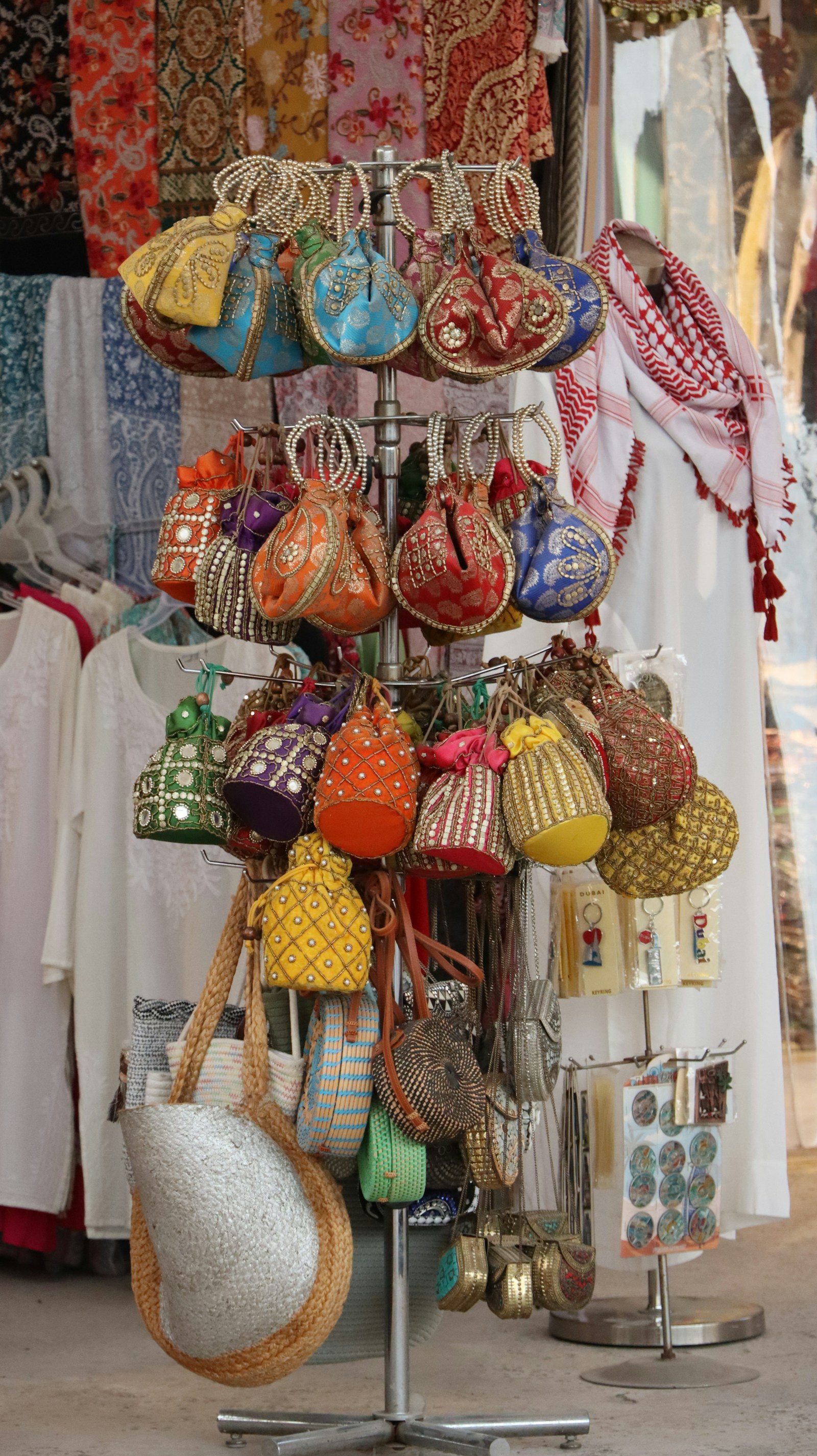 Bolsas saco coloridas com miçangas e cordões penduradas em arara