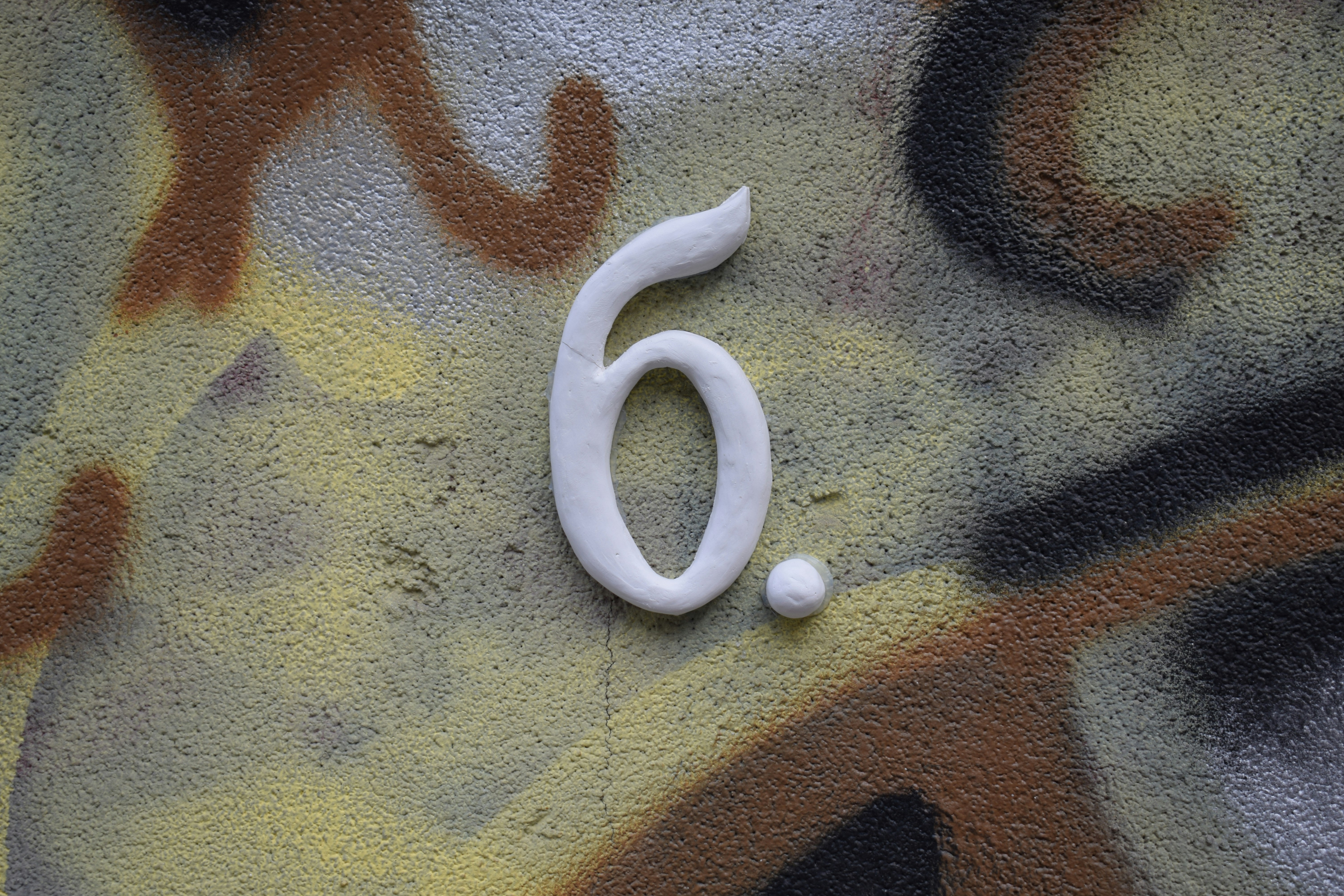 White number six on a graffiti wall.