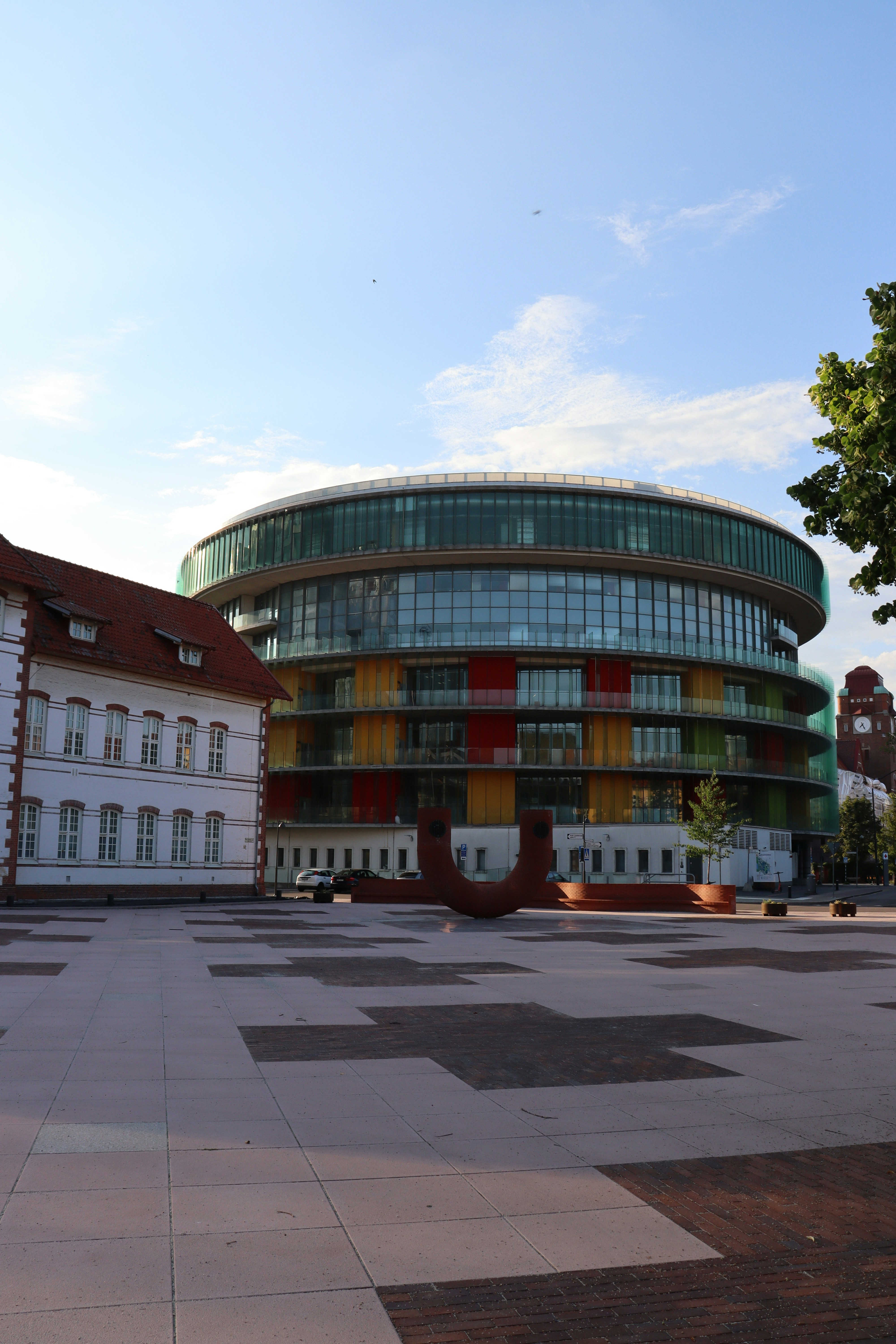 Moderner Rundbau mit farbiger Fassade und Altbau