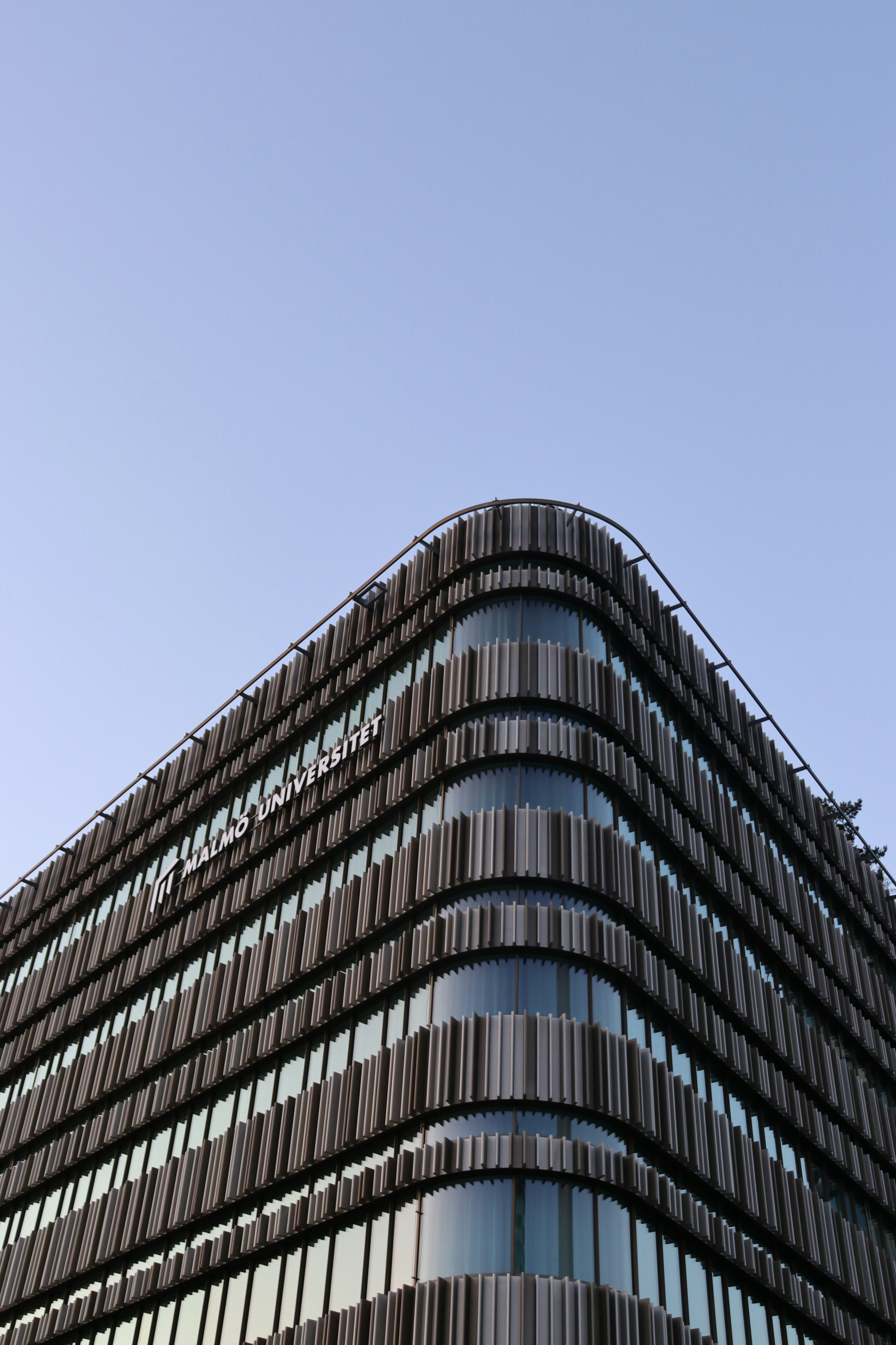 Modernes Gebäude mit gebogener Glasfassade gegen den Himmel.