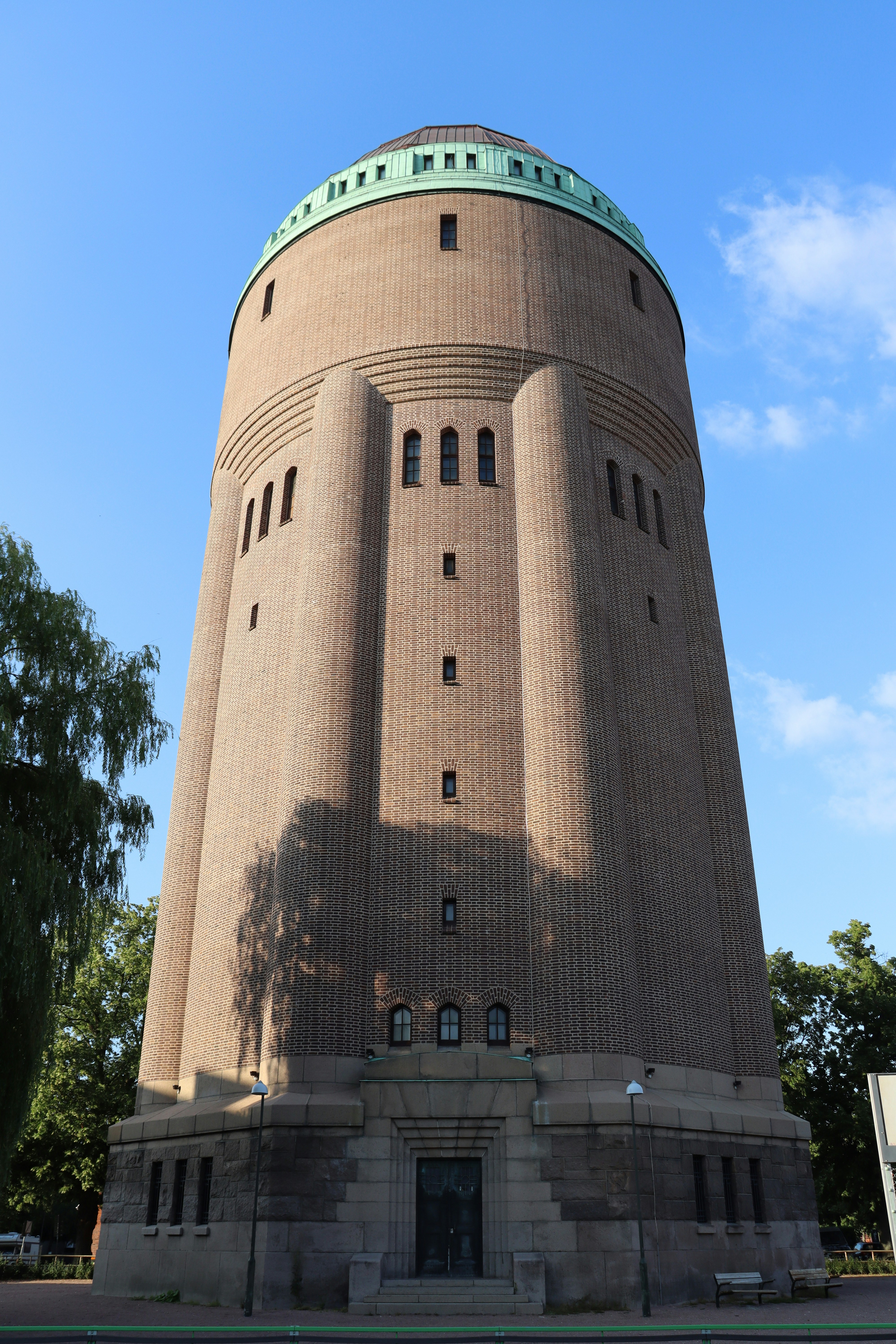 A tall brick water tower with a green dome.