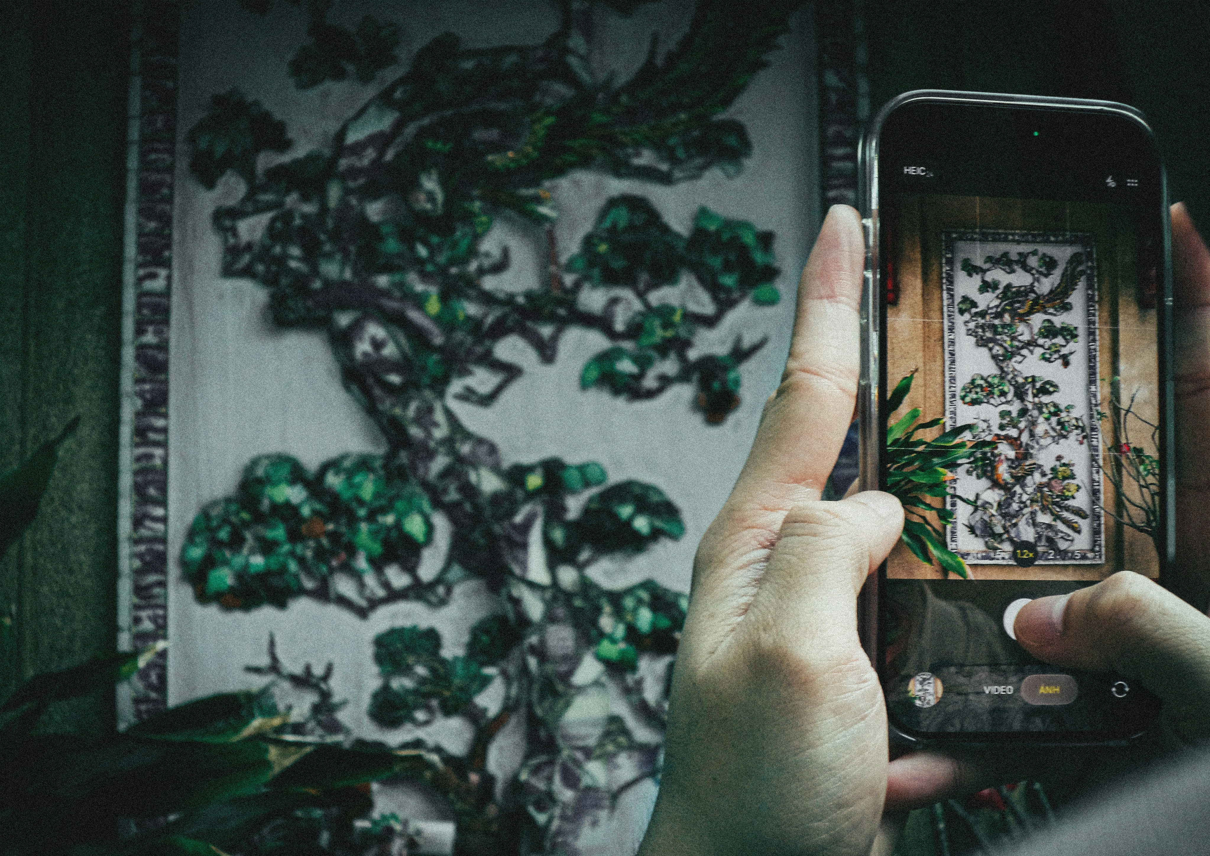 Person taking a picture of a detailed tree artwork.