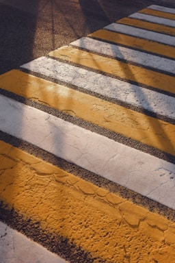 Yellow and white stripes of a crosswalk on asphalt