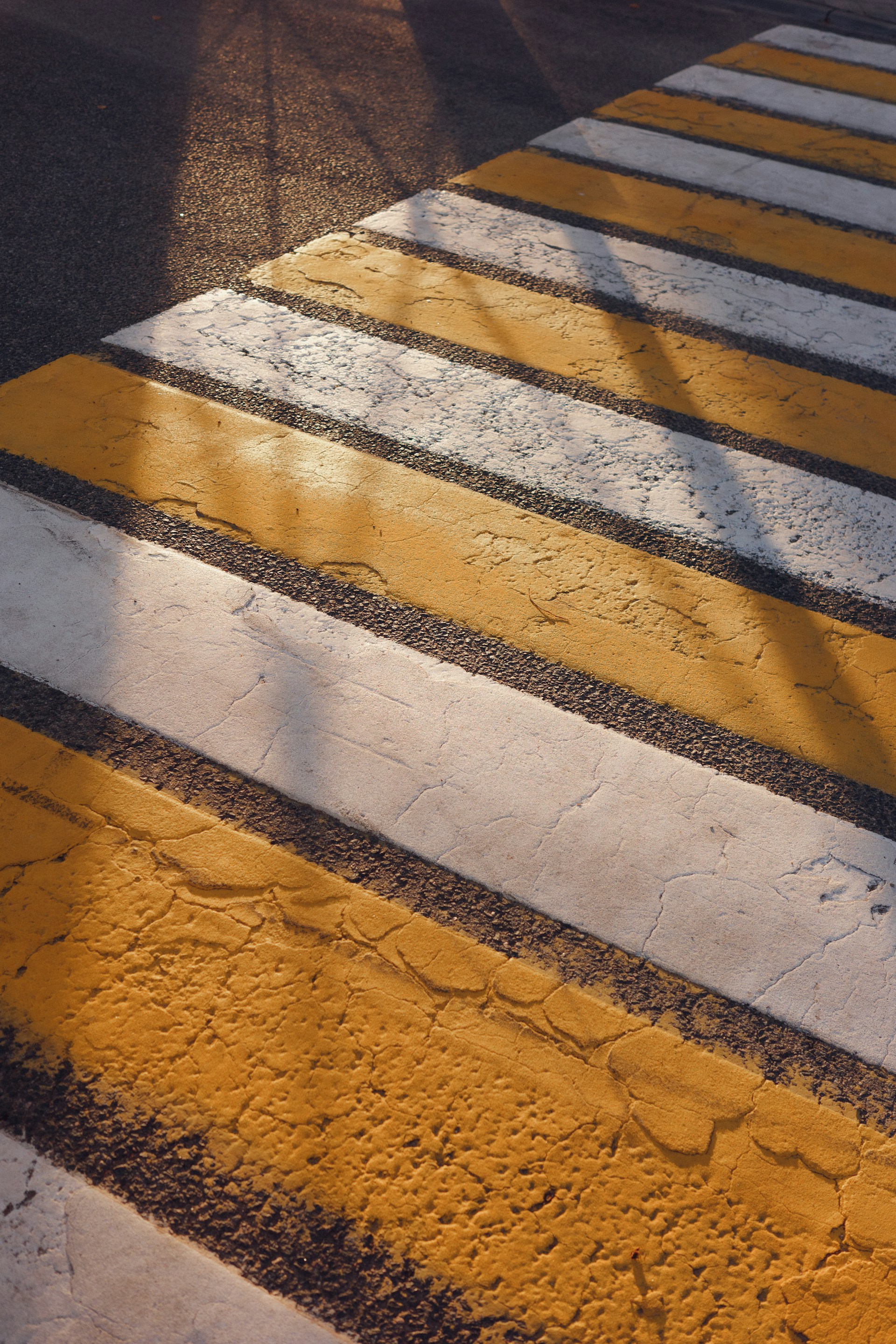 Yellow and white stripes of a crosswalk on asphalt