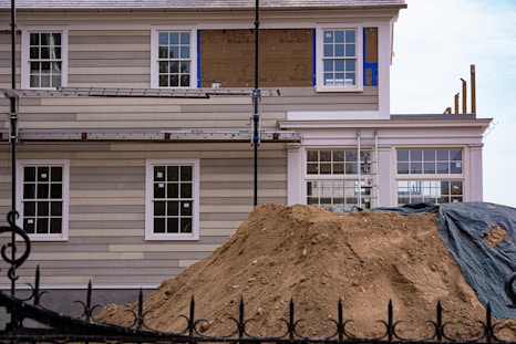 House under renovation with scaffolding and dirt pile.