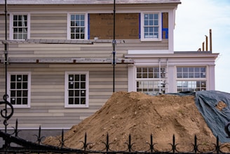 House under renovation with scaffolding and dirt pile.