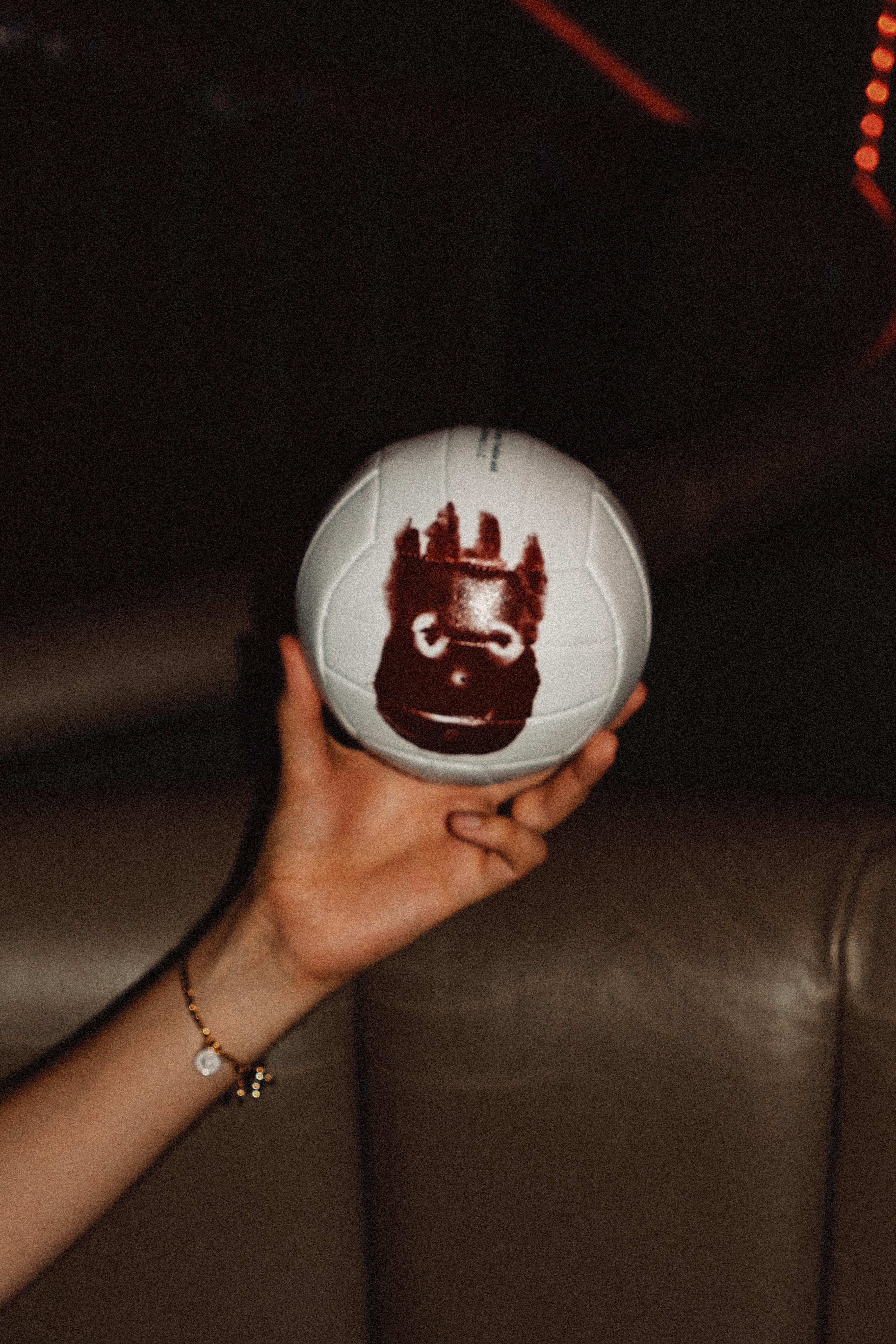 Hand holding a white volleyball with a cartoon face.