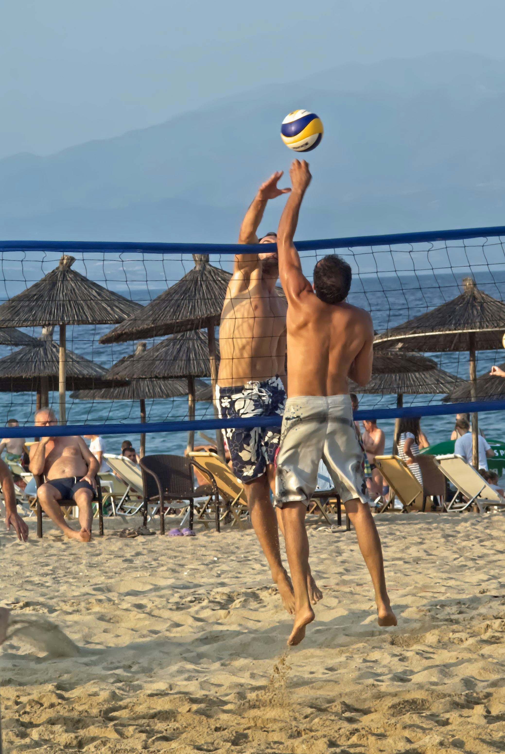 due uomini che giocano a pallavolo su una spiaggia assolata.