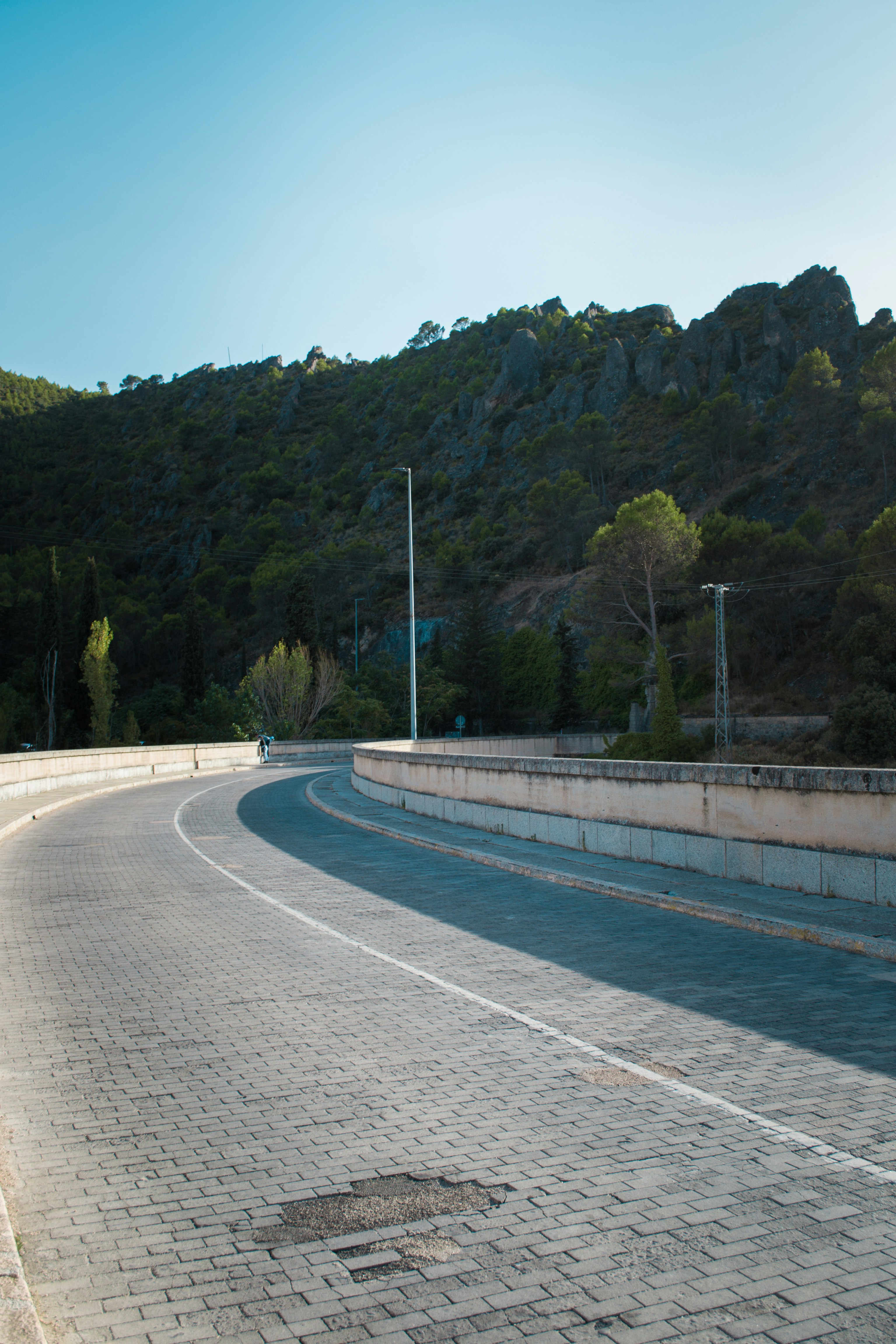 Curving road with mountains and trees under blue sky
