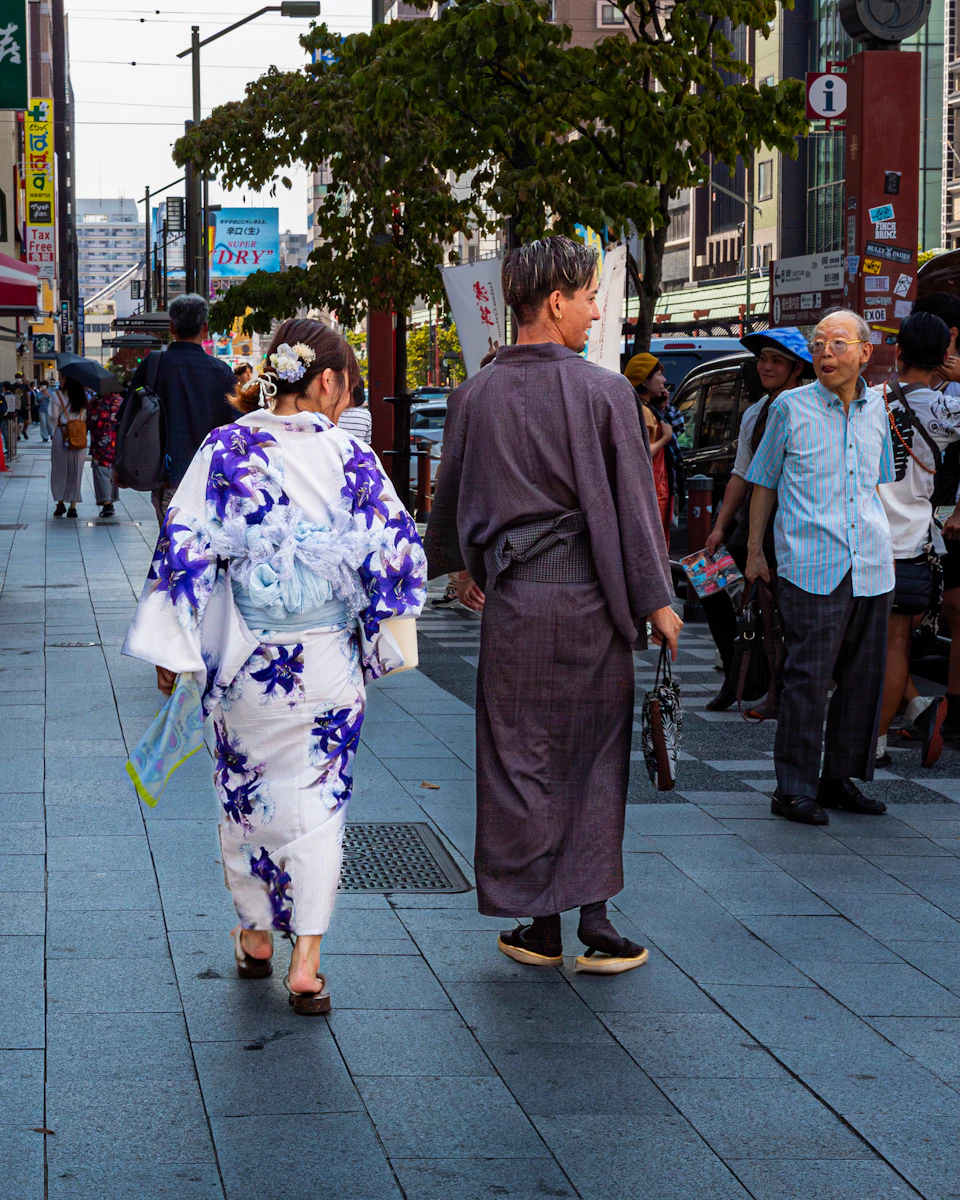 A couple in traditional cotton yukata walking a Tokyo street on a summer evening