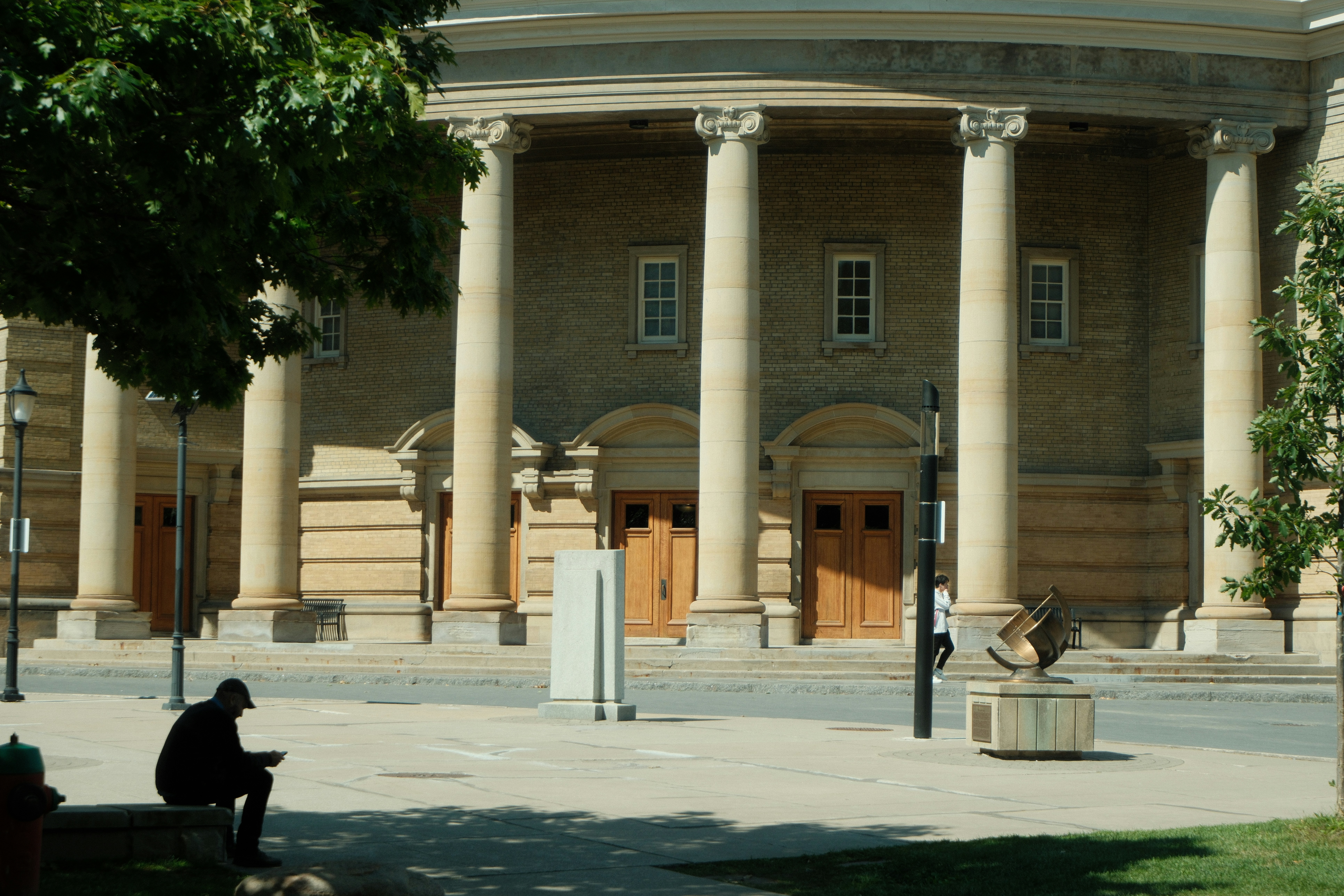 Building with large columns and a person sitting outside. photo – Free ...