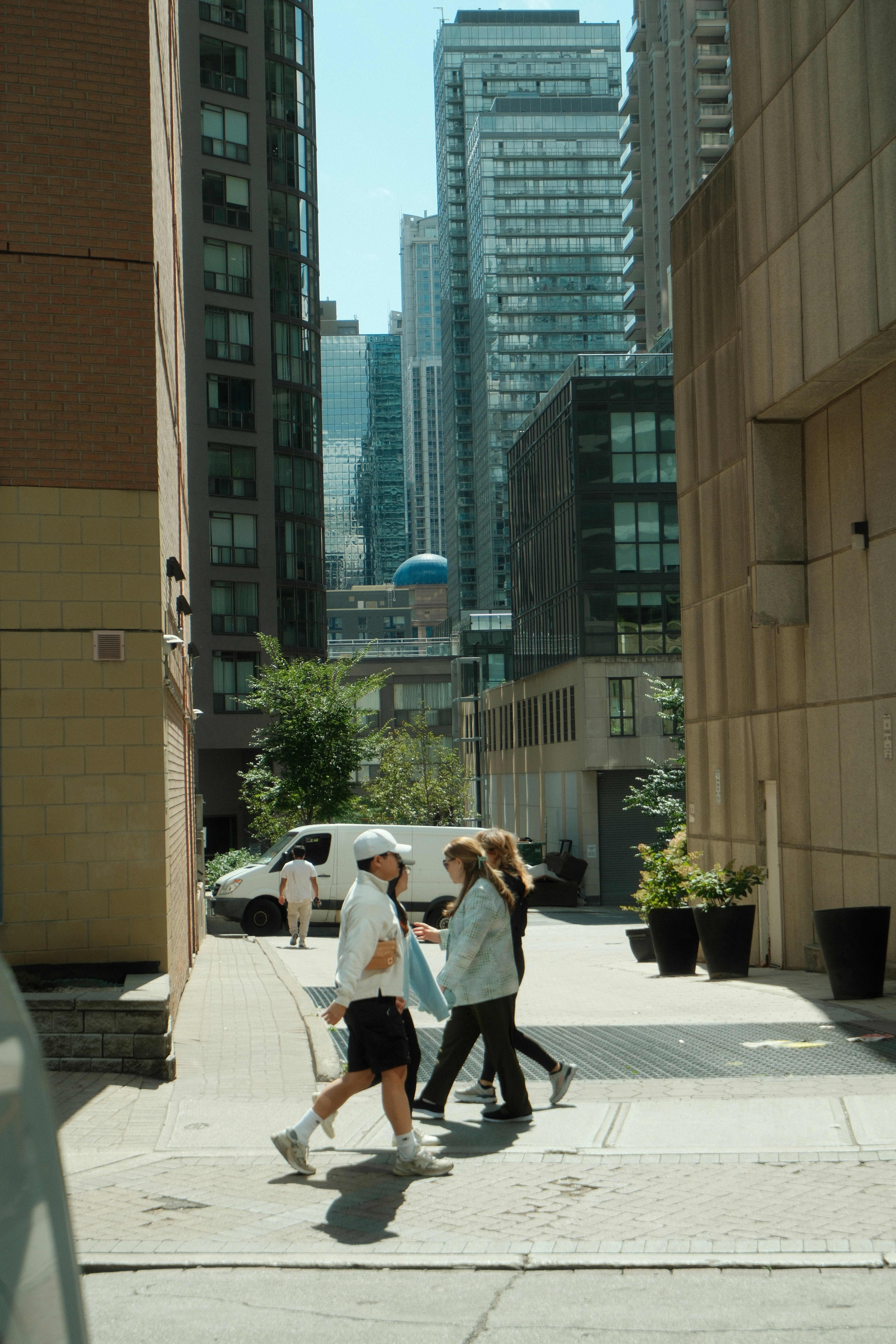 People walk down a city street with tall buildings.