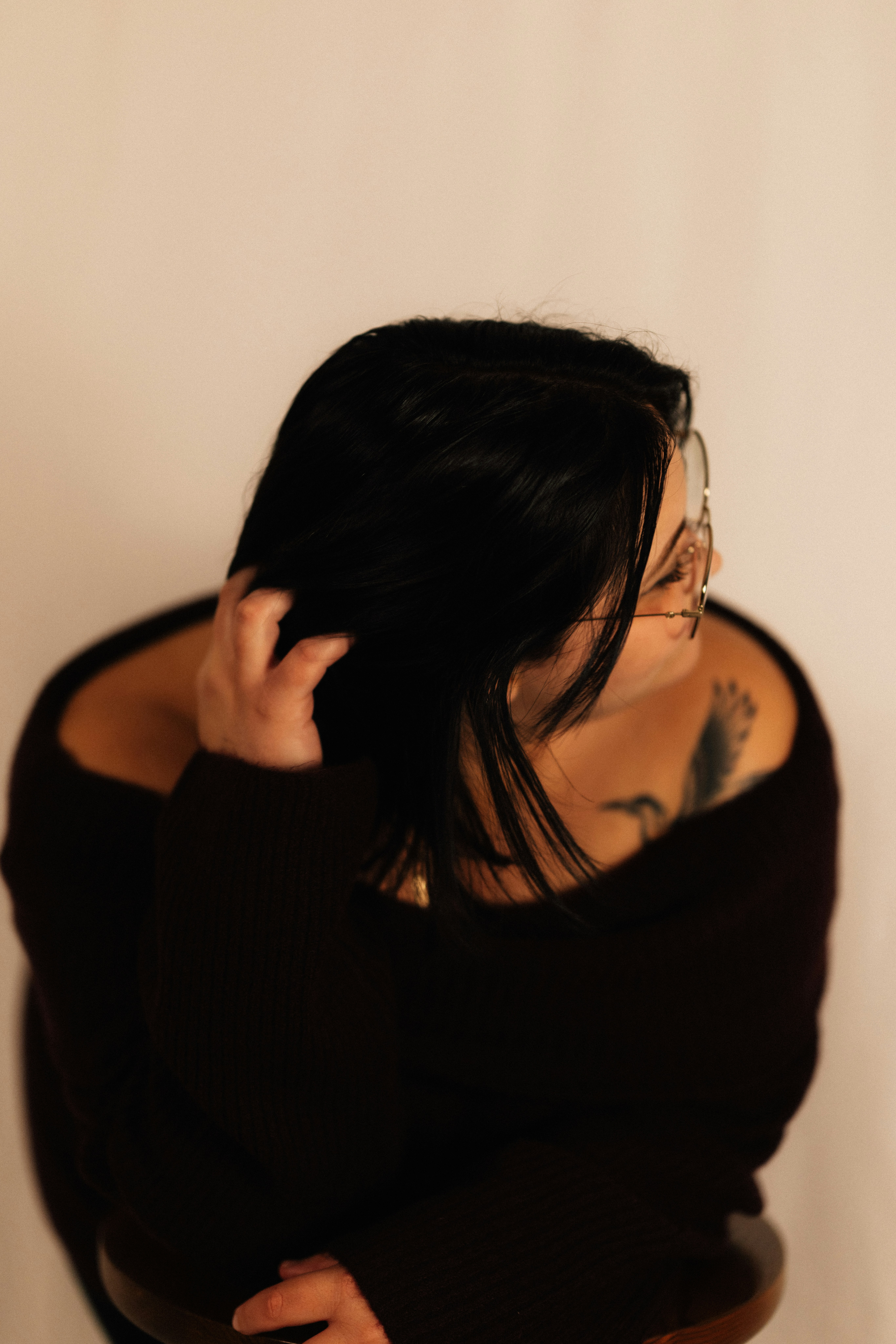 Woman with dark hair and glasses touching hair