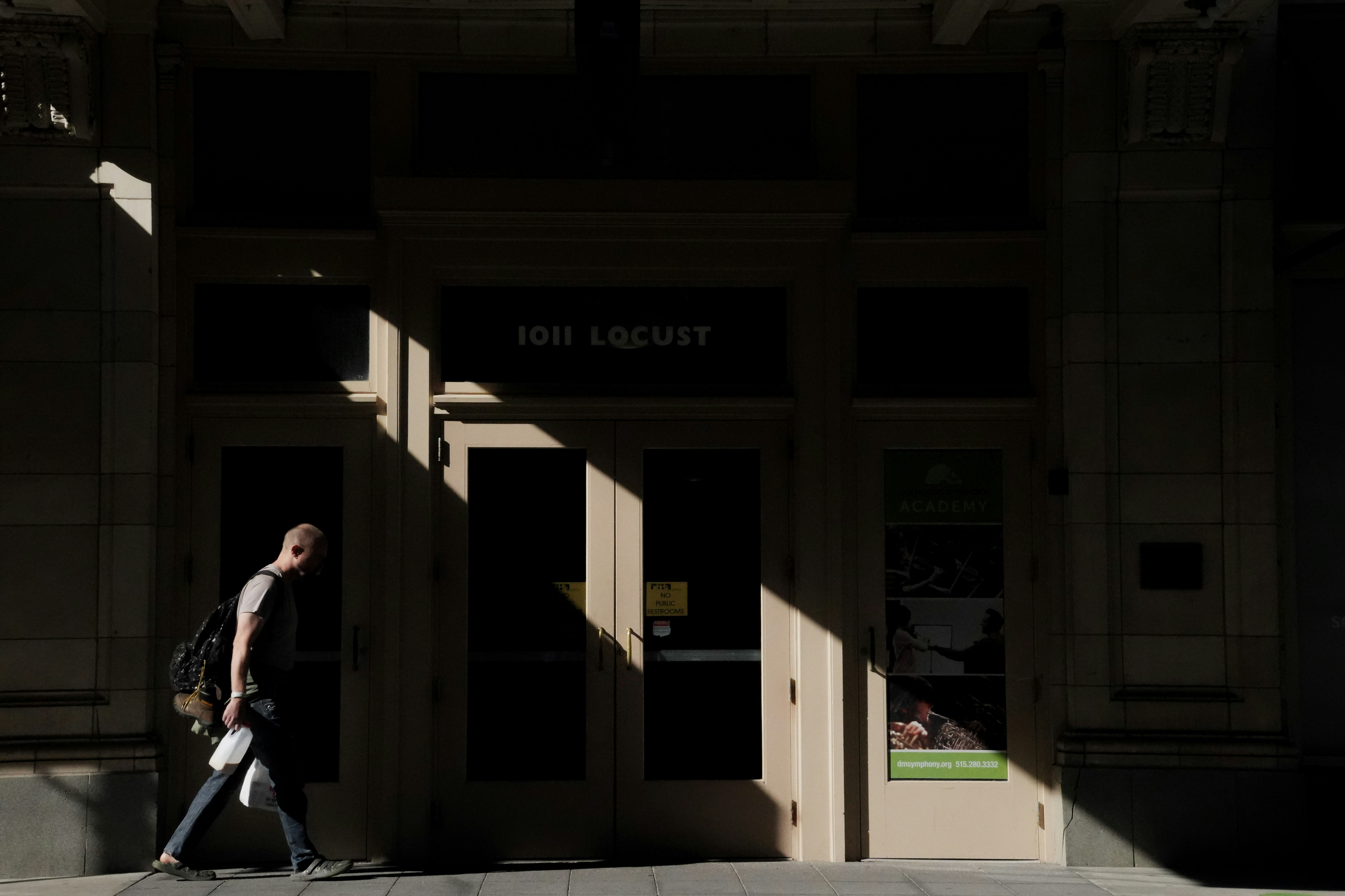 人は強い影のある建物の入り口を通り過ぎます。