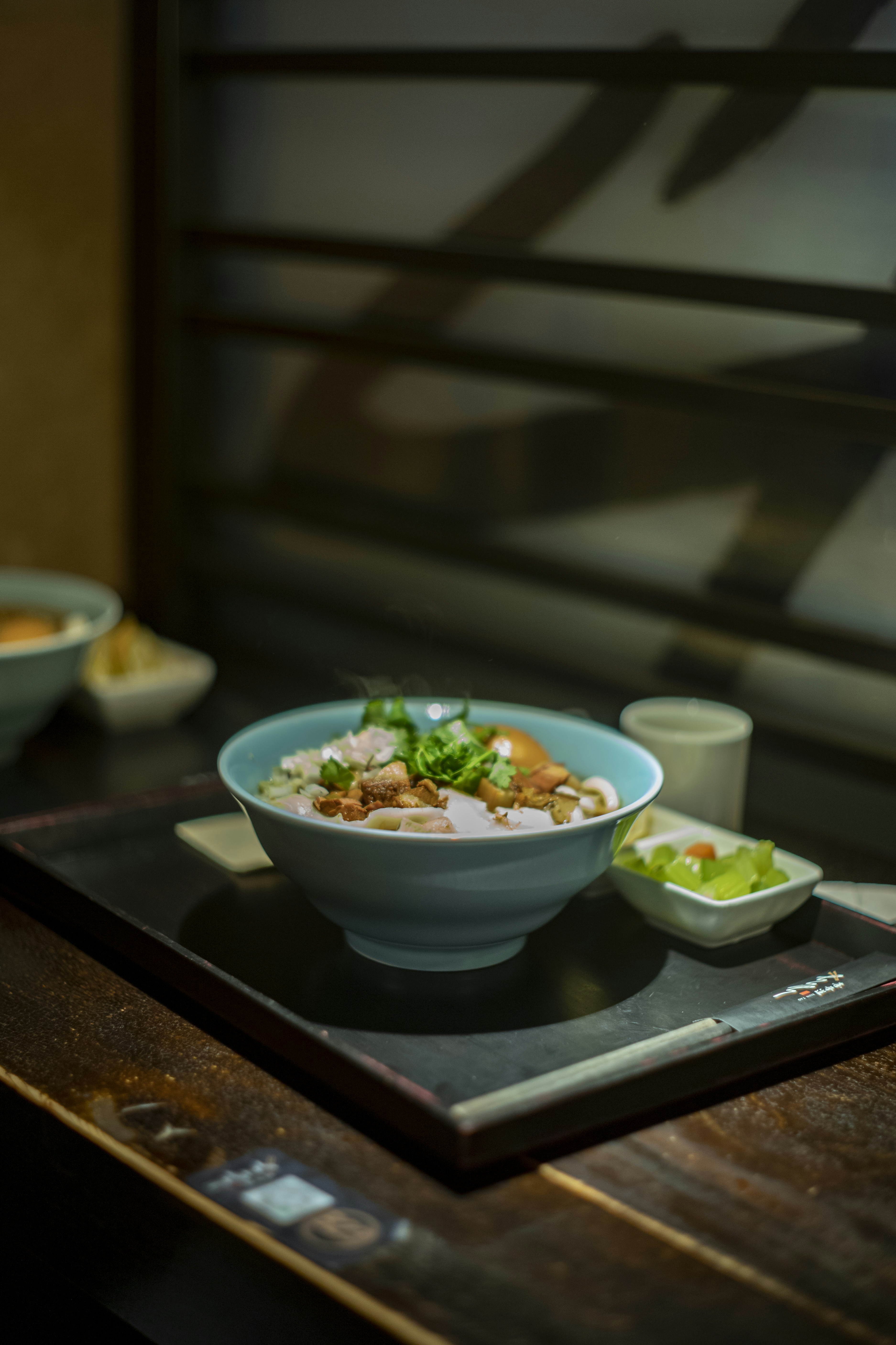 A bowl of noodles with toppings and a side dish.