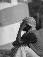 Man in turban resting head on hand outdoors.