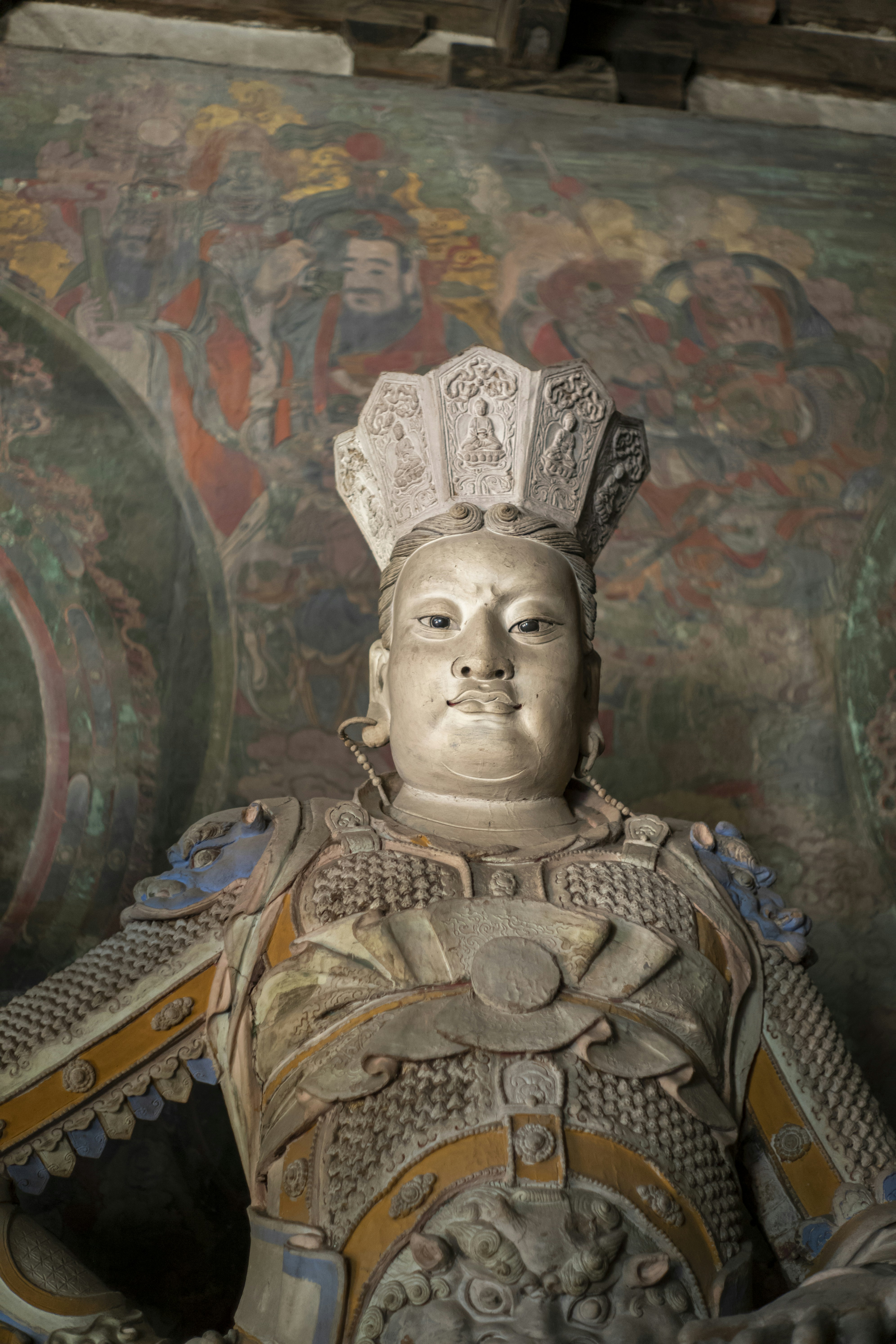 Ancienne statue en pierre d’un guerrier en armure ornée.
