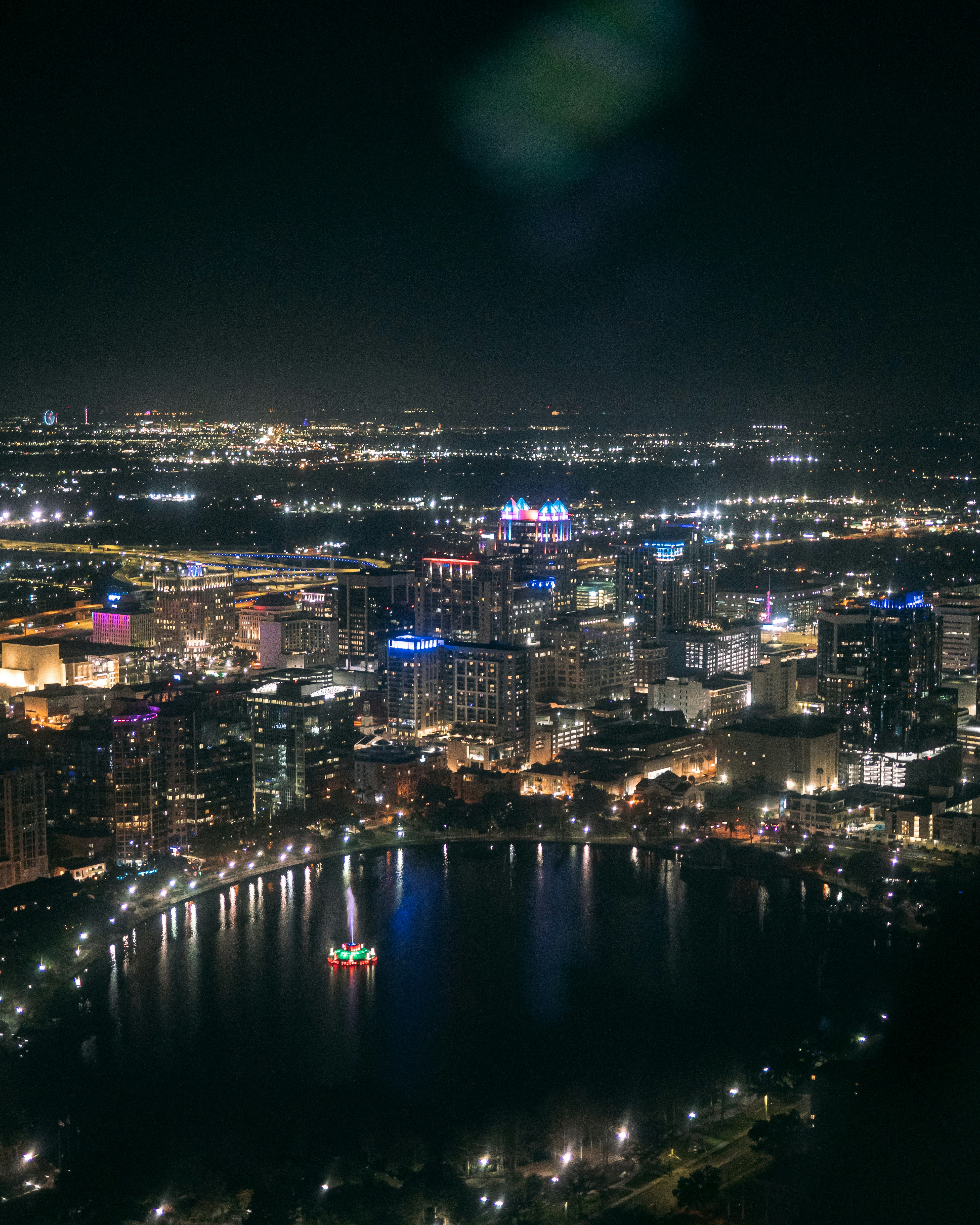 City skyline illuminated at night with a lake.