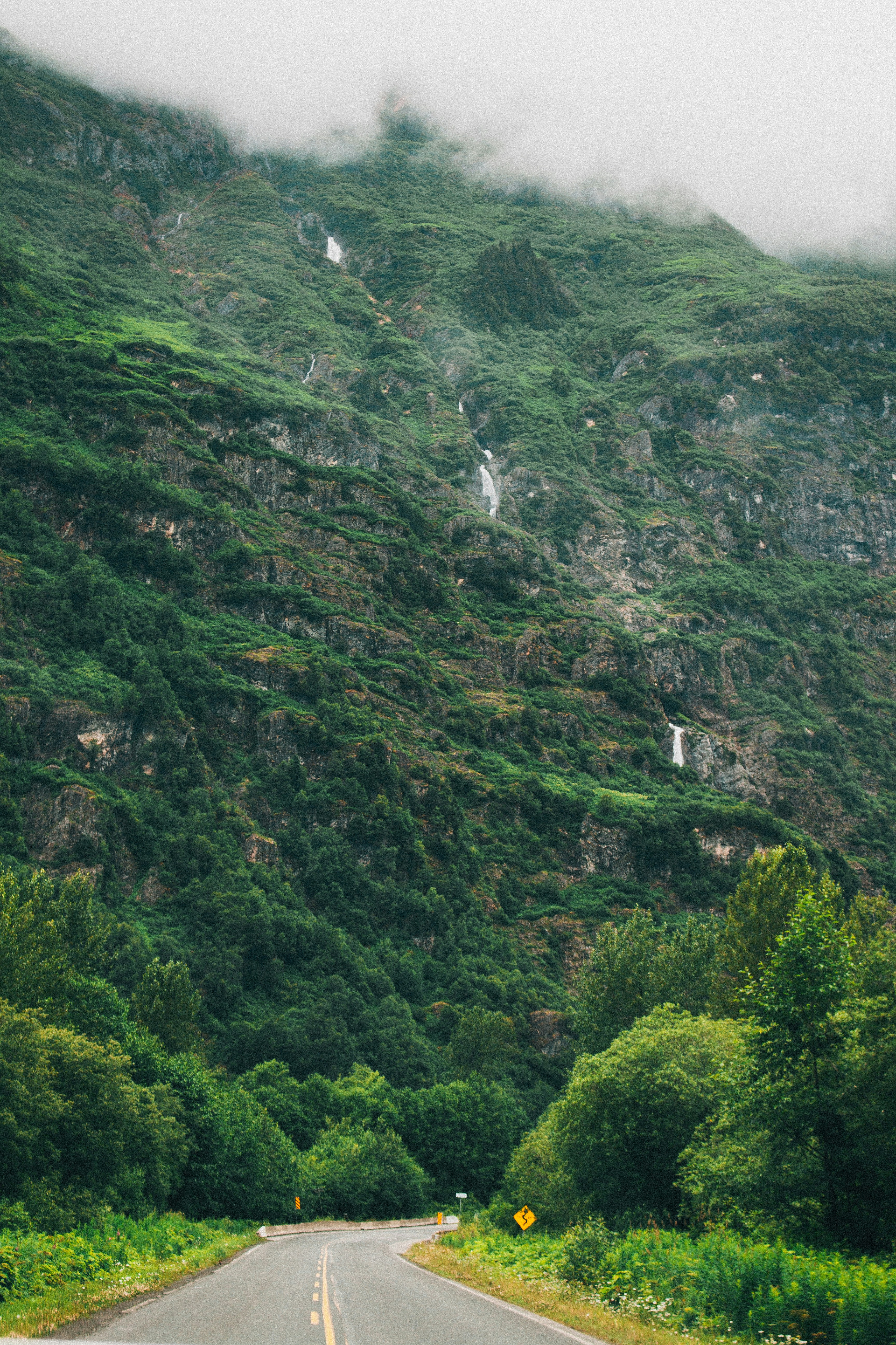 Green mountains with waterfalls and a winding road.