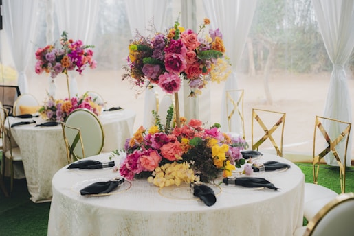 Elegant tables with vibrant floral centerpieces at an event.