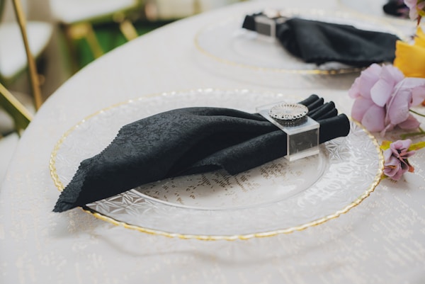 Black napkin on a clear plate with gold rim.