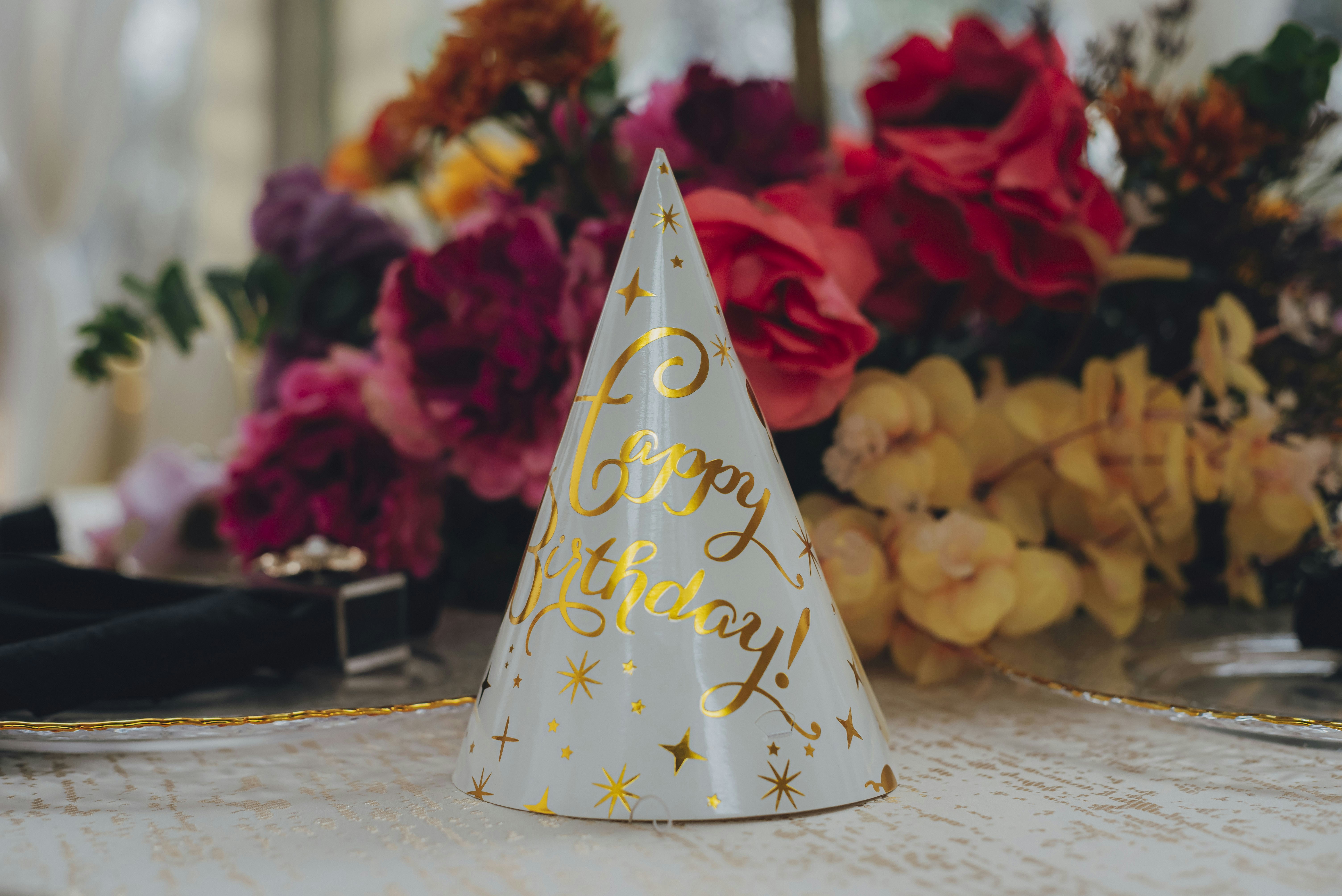 Chapéu de festa com mensagem de "feliz aniversário" e flores.