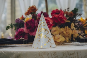 Birthday hat with flowers on a decorated table.