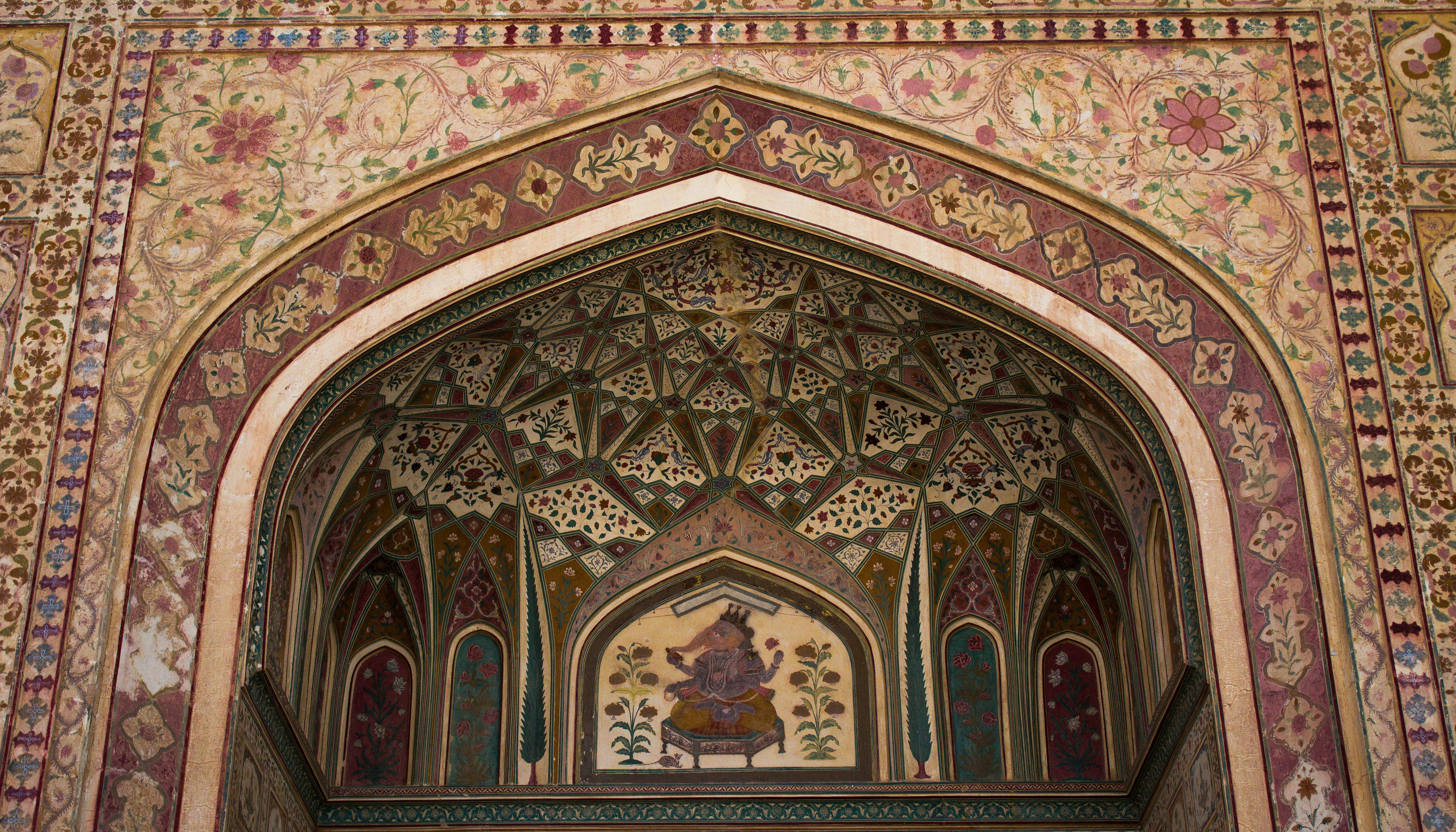 Arco ornamentado con intrincados patrones florales y pintura central.