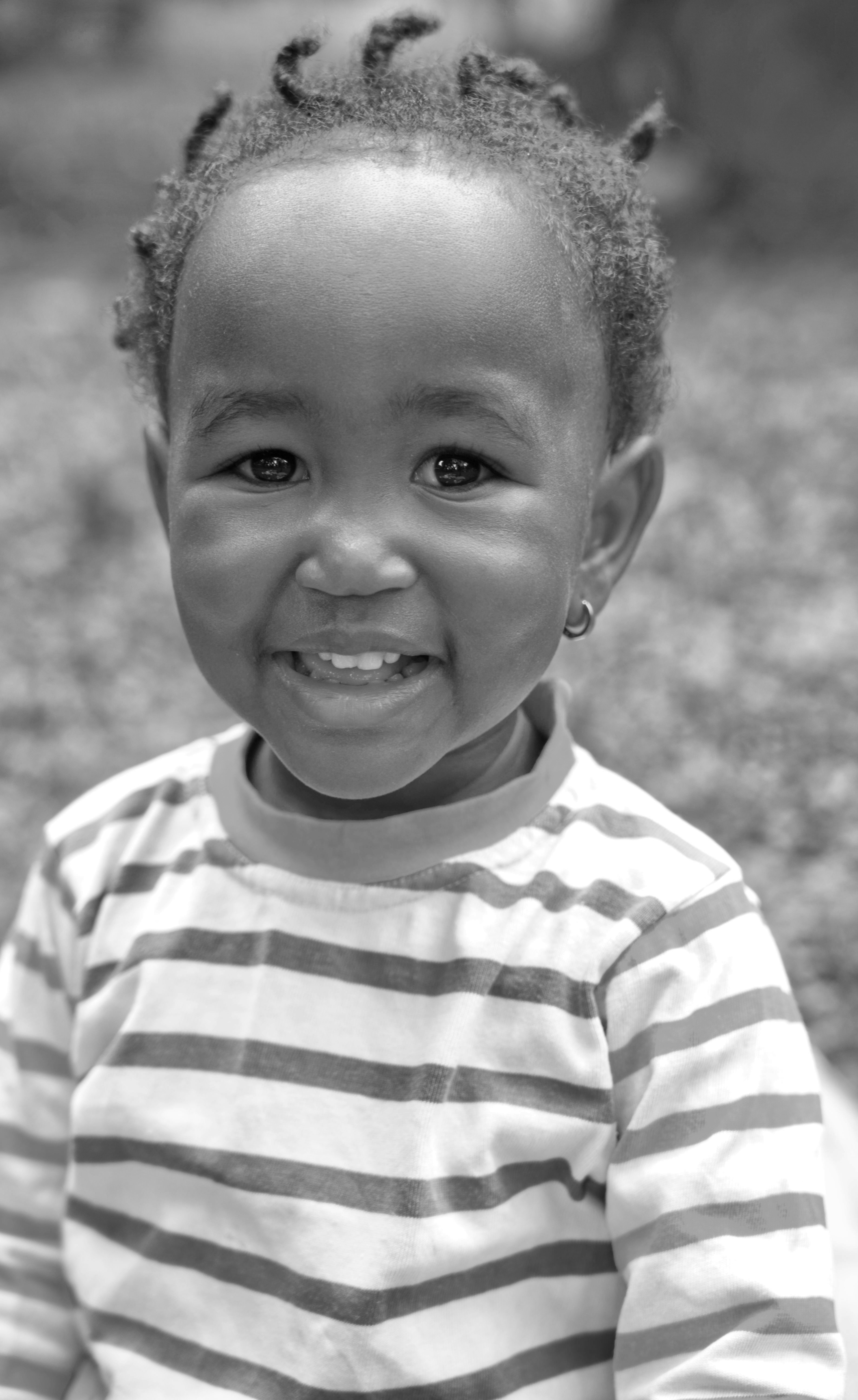 A young child with braided hair smiles broadly.