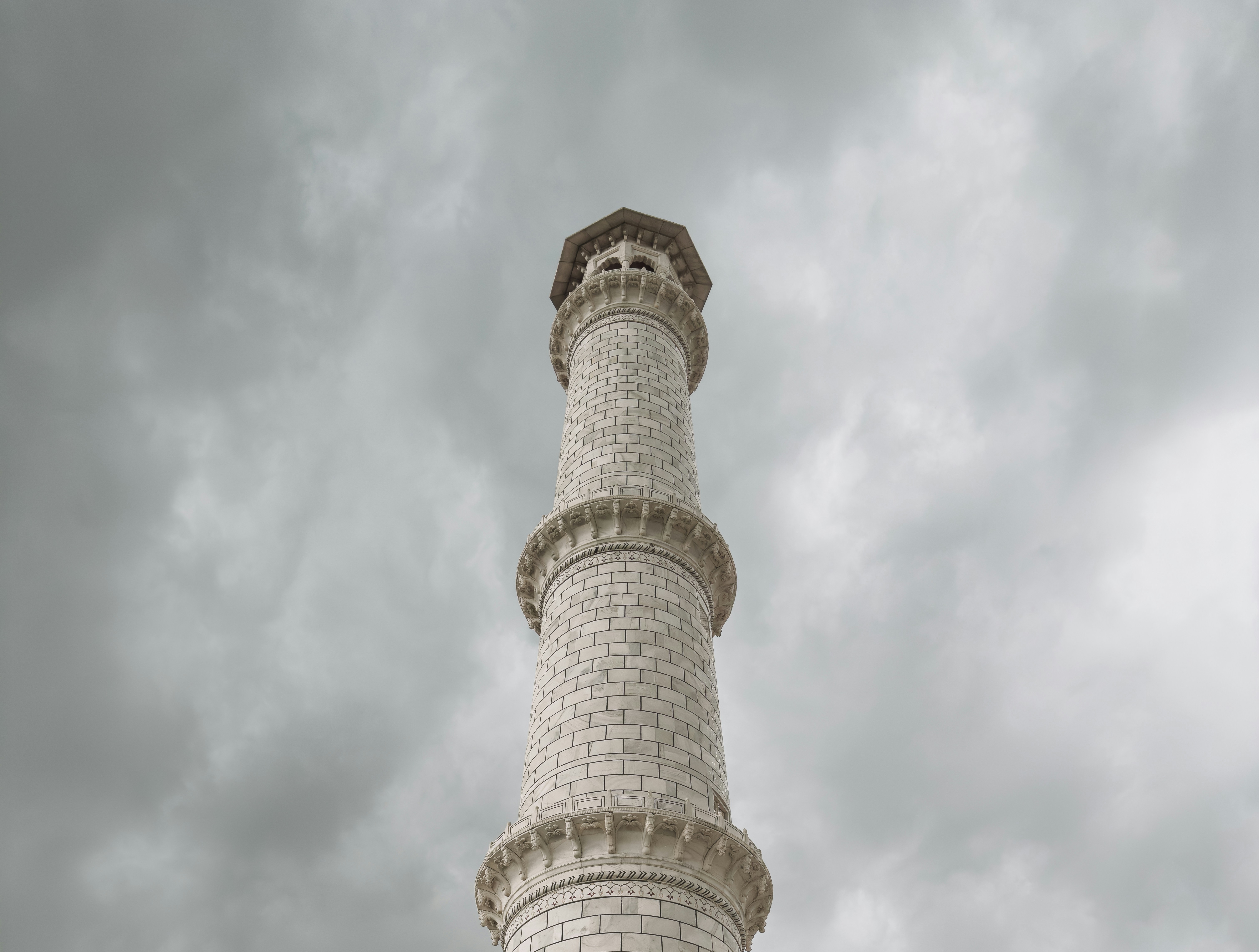 Tall marble minaret against a cloudy sky