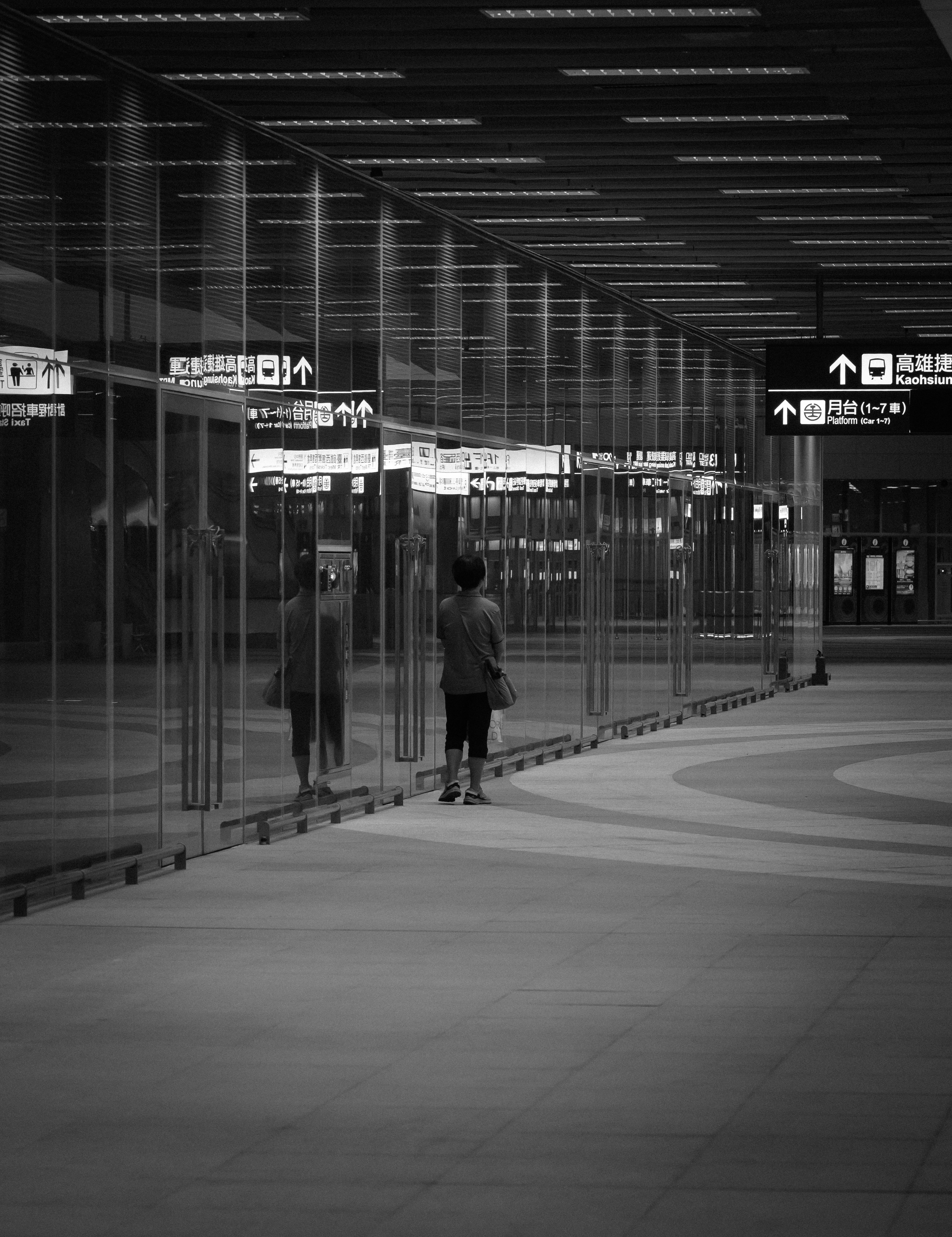Person walks down a modern hallway with glass walls.