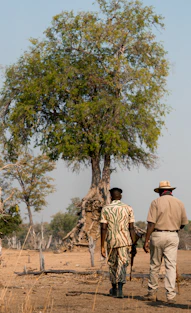 Two men walk through a dry, grassy landscape.