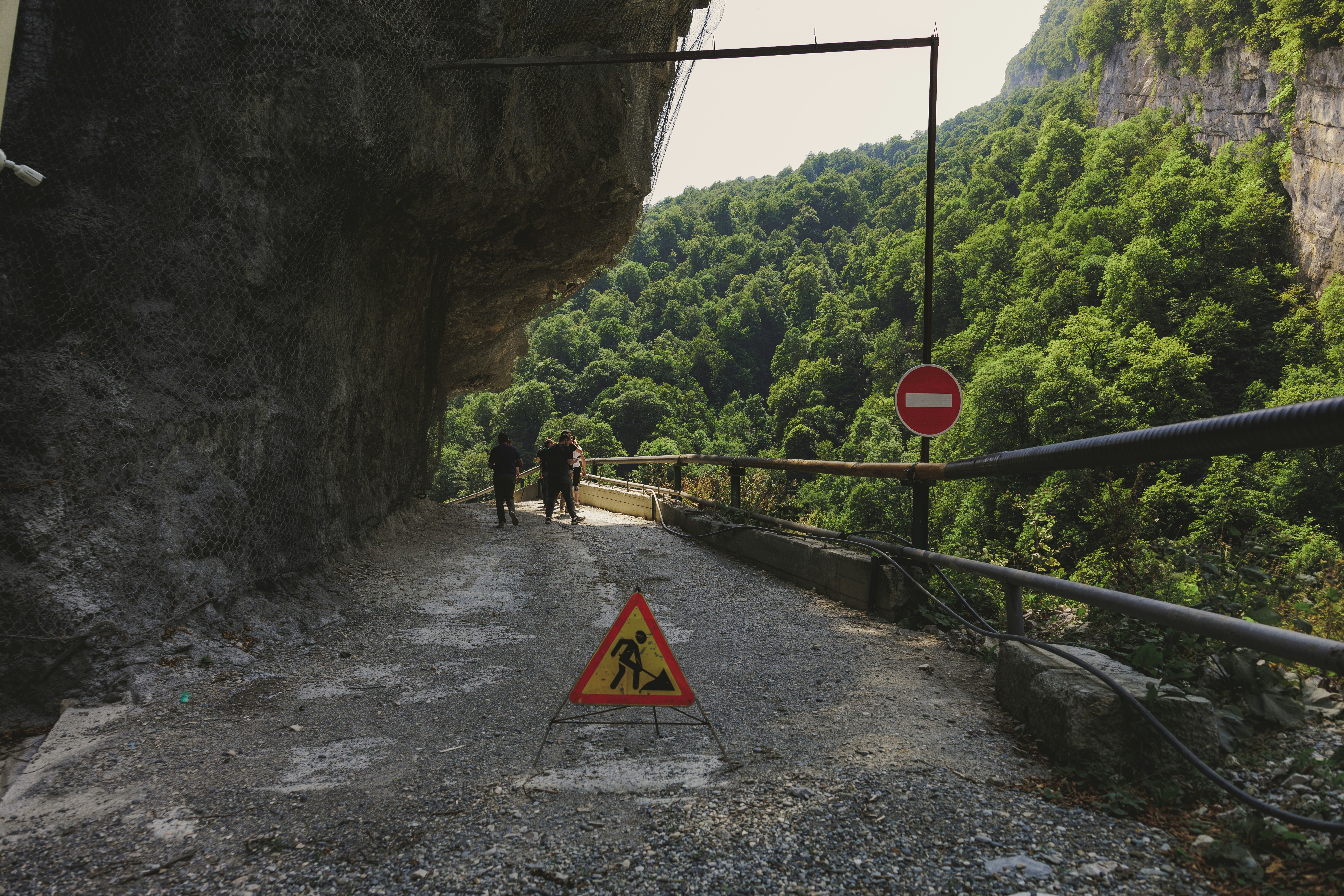 Two people walk on a wet path with construction sign.