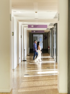 Couple walking down a sunlit hallway indoors.