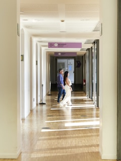 Couple walking down a sunlit hallway indoors.