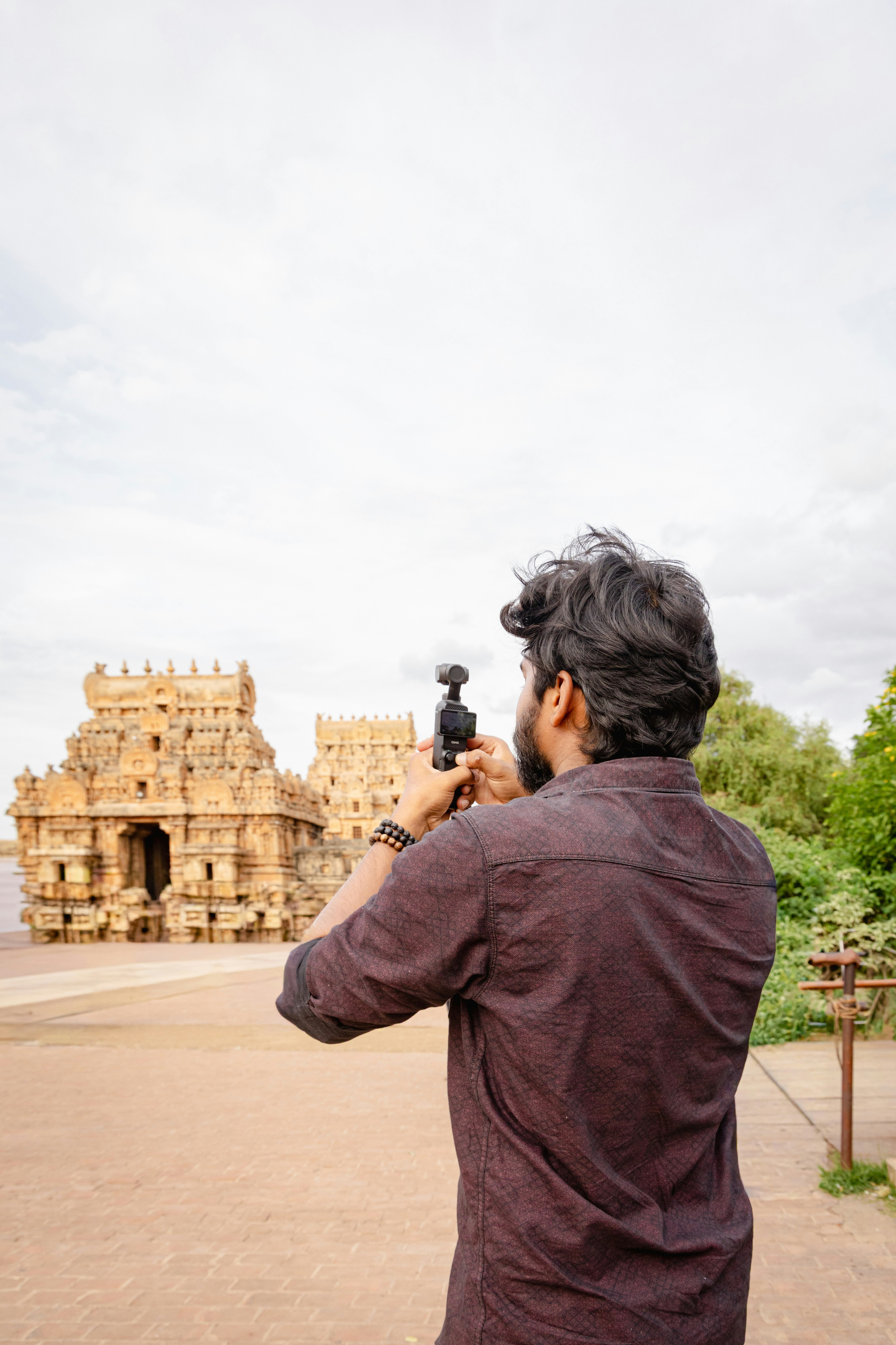 Hombre filmando un templo antiguo con cámara de mano