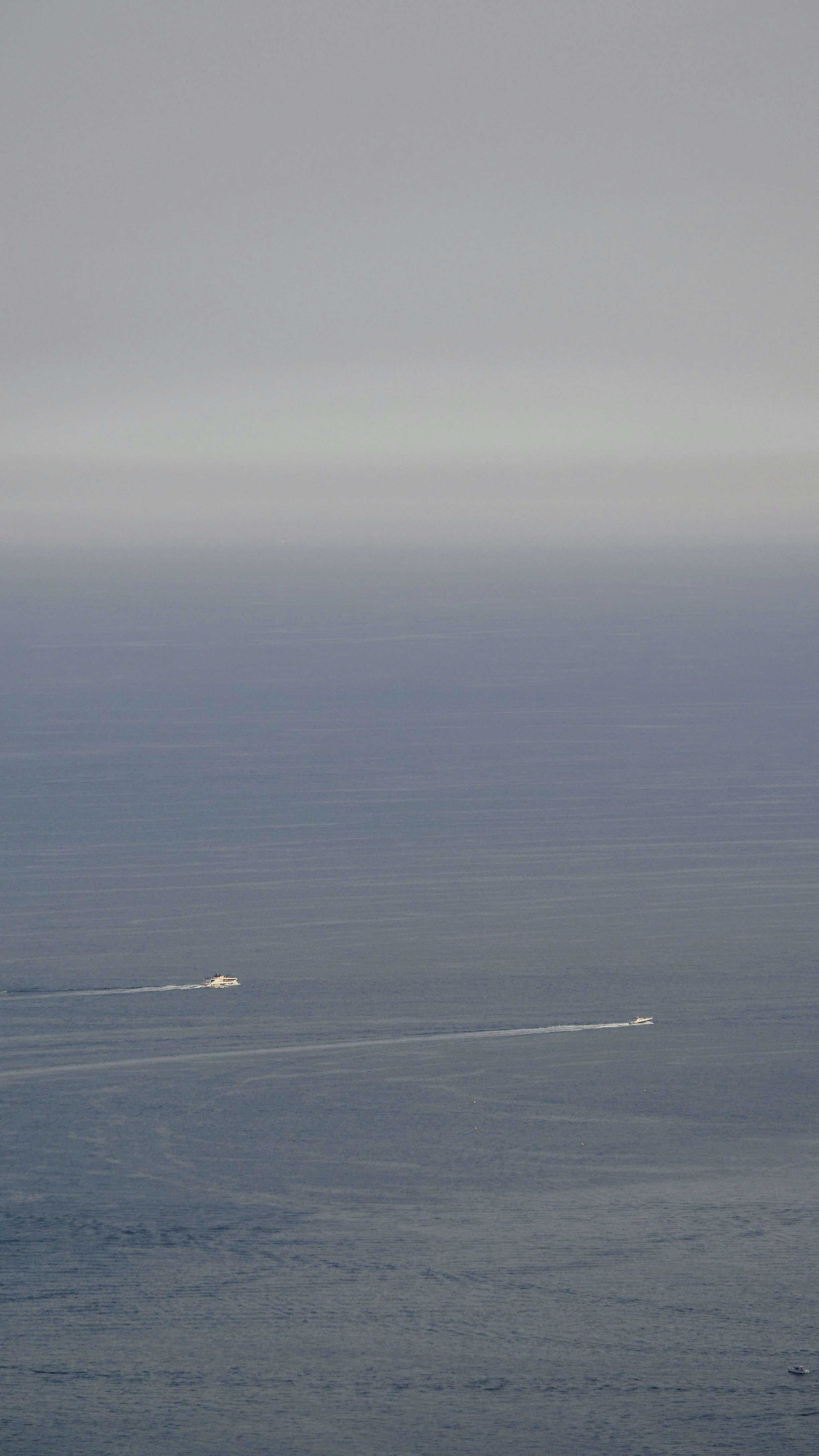 Due barche che navigano su un oceano blu calmo.