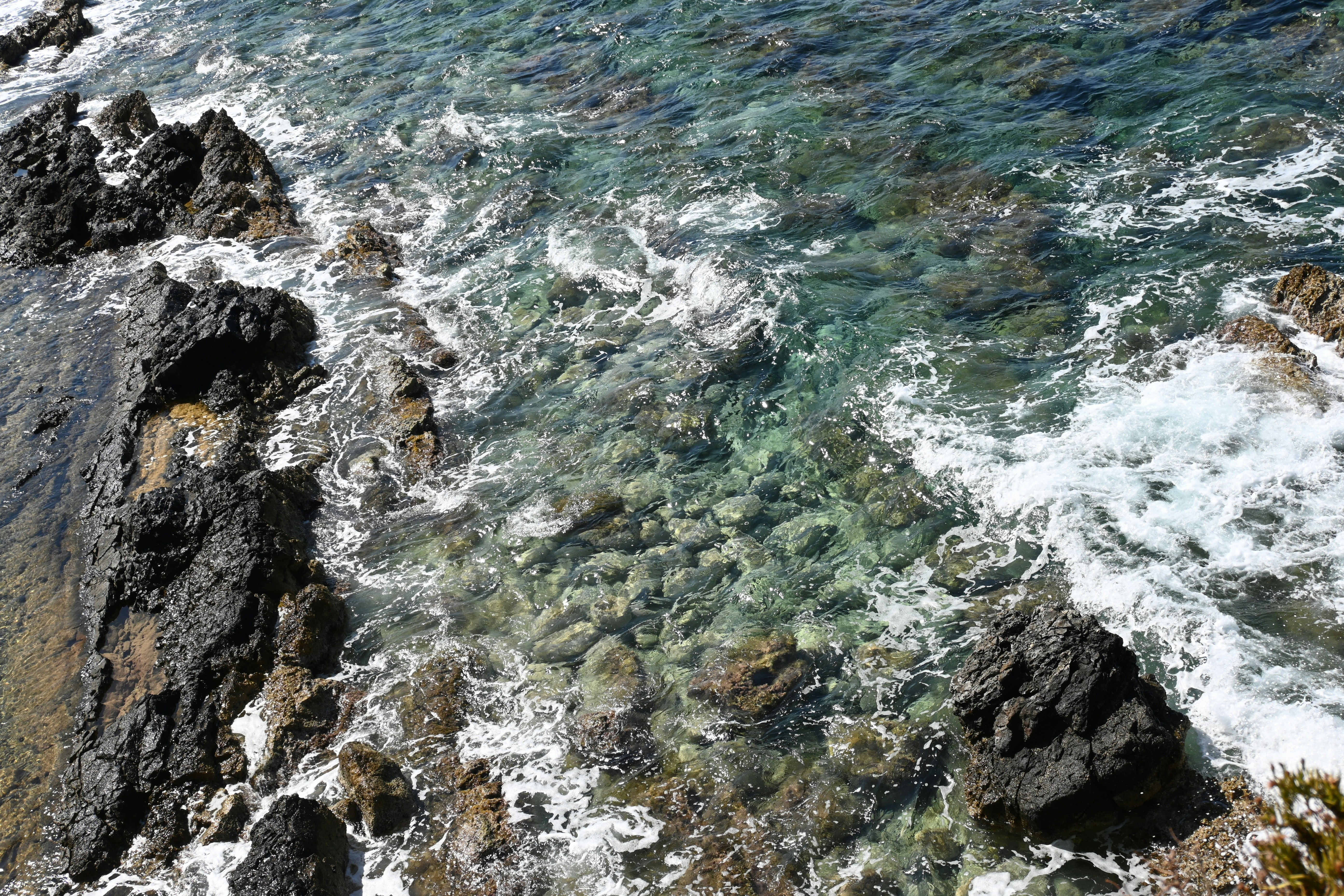 Waves crashing on rocky coastline with clear water