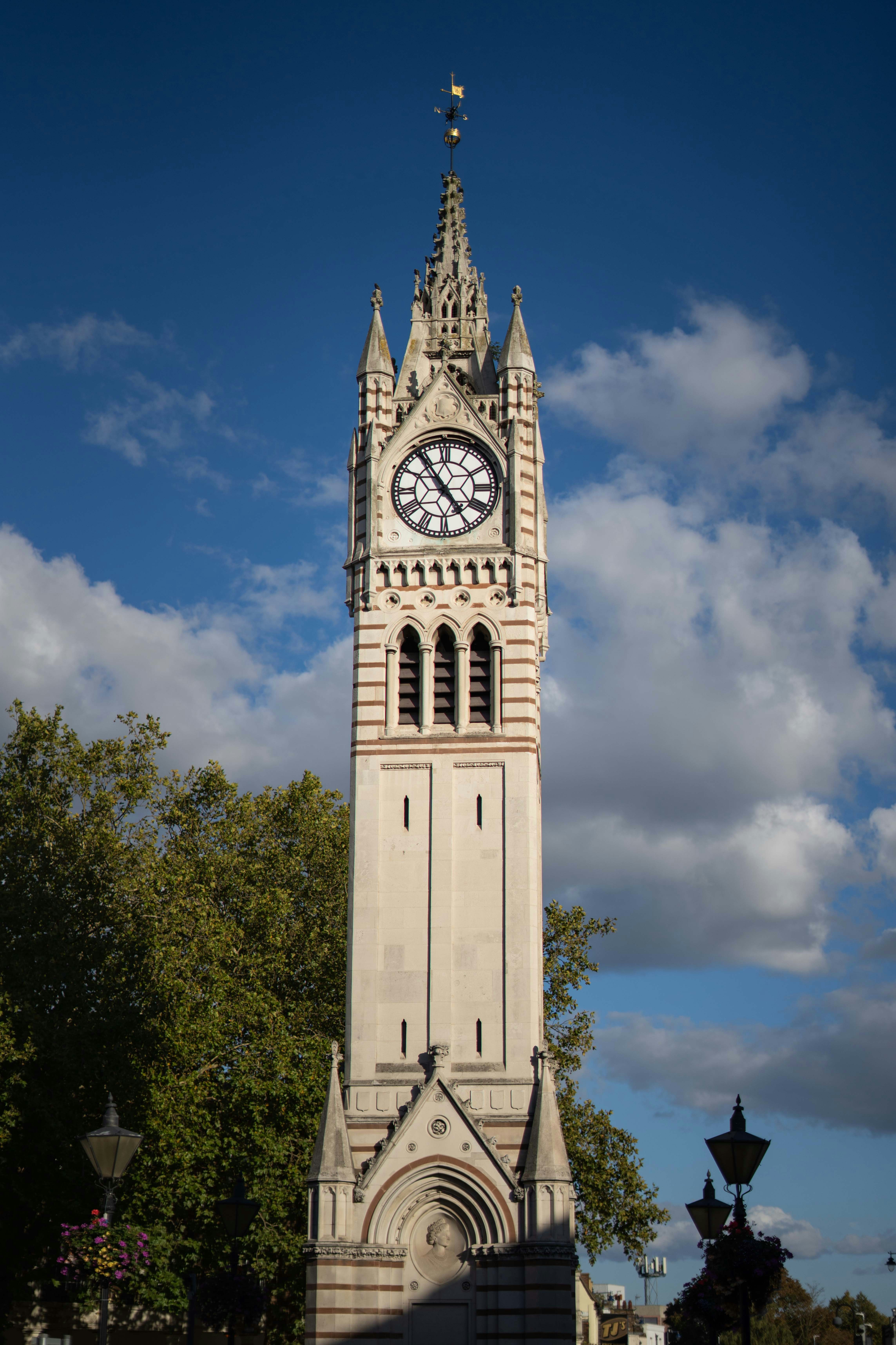 Tall clock tower against a blue sky with clouds.
