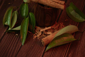 Cinnamon sticks and leaves on a wooden surface.
