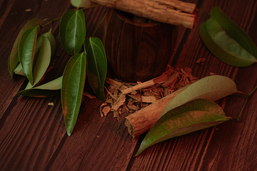 Cinnamon sticks and leaves on a wooden surface.