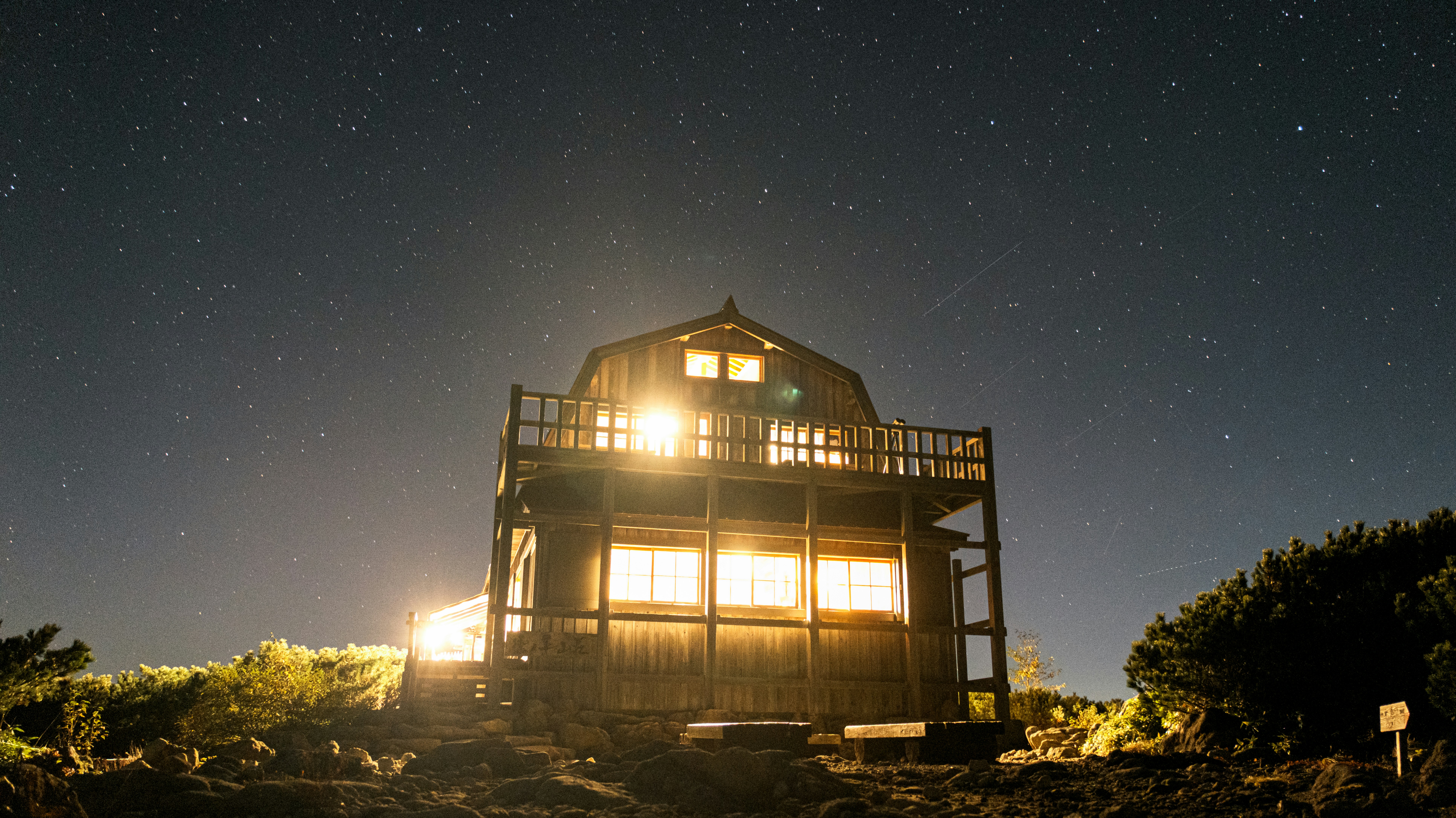 Wooden cabin illuminated under a starry night sky.