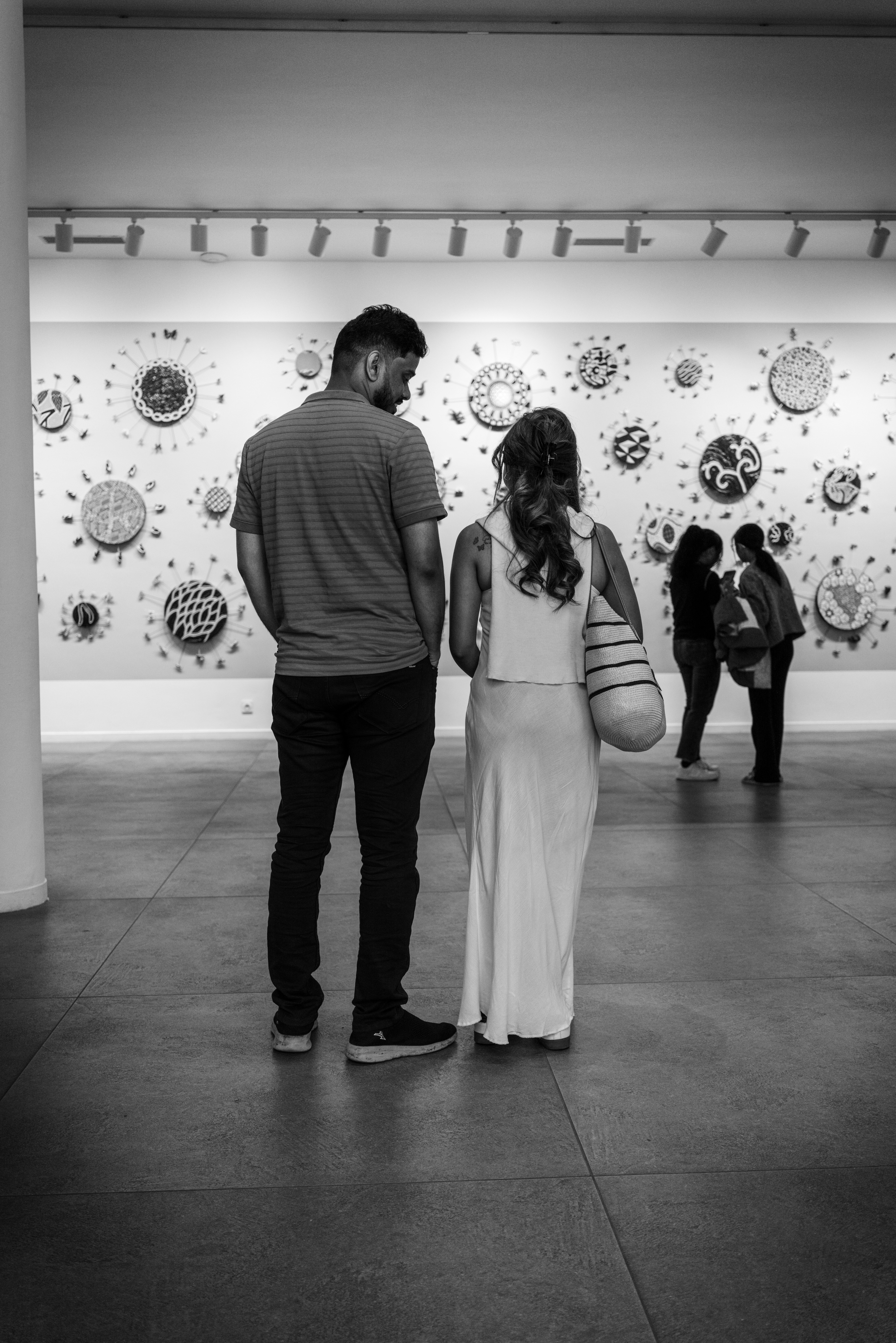 Couple viewing circular art on gallery wall