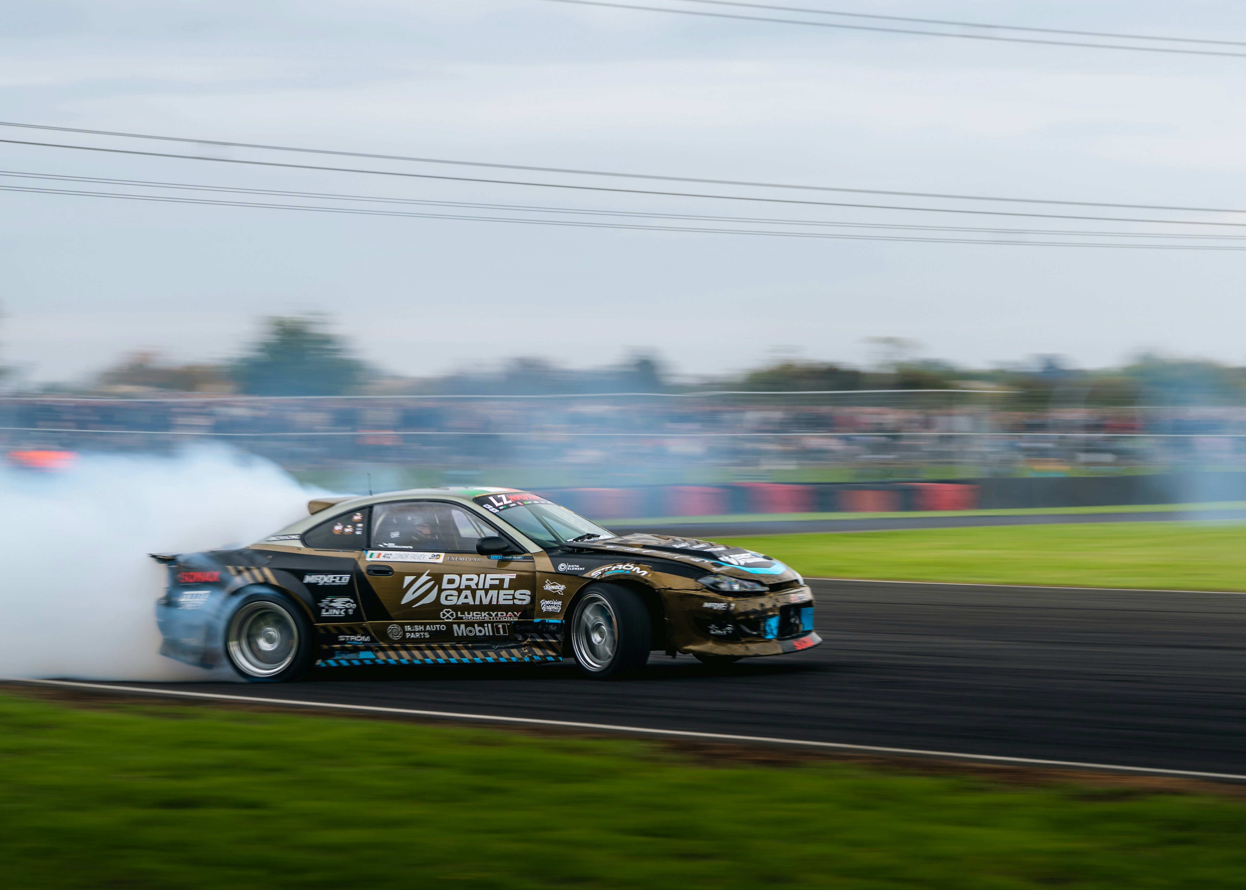 A race car drifts around a corner, creating smoke