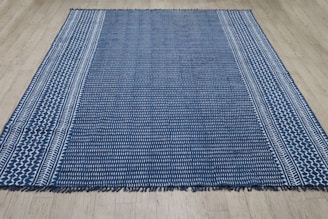 A blue and white striped rug on a wooden floor.